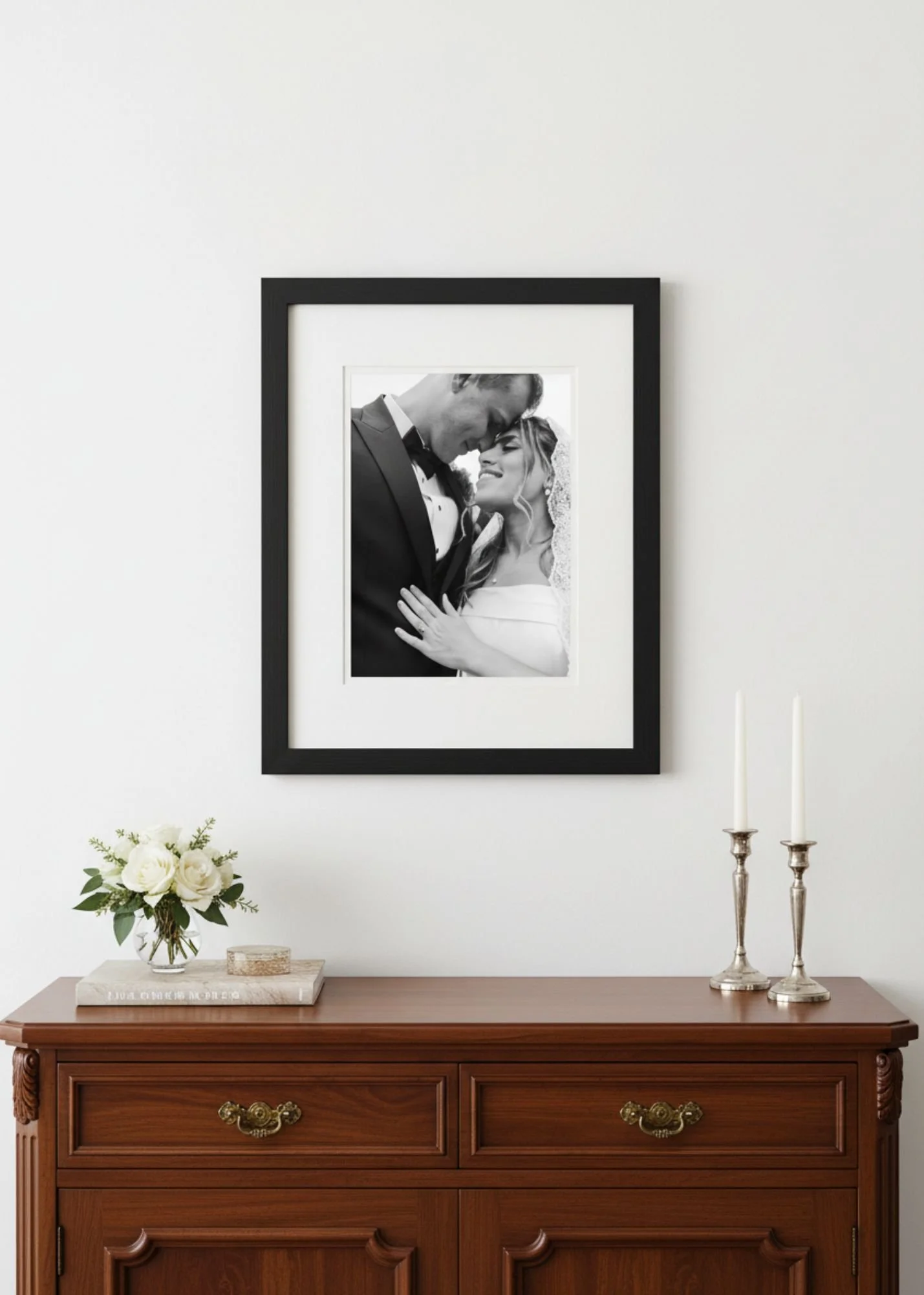 A large framed wedding photo display hanging above a dark wooden dresser.
