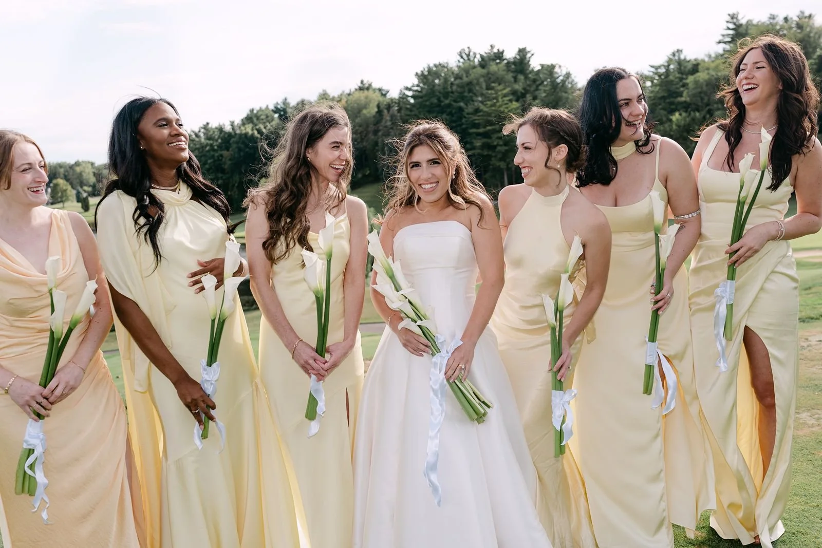 True to color wedding photographer Alaina Miller photographing a smiling bride and her bridesmaids wearing butter yellow.