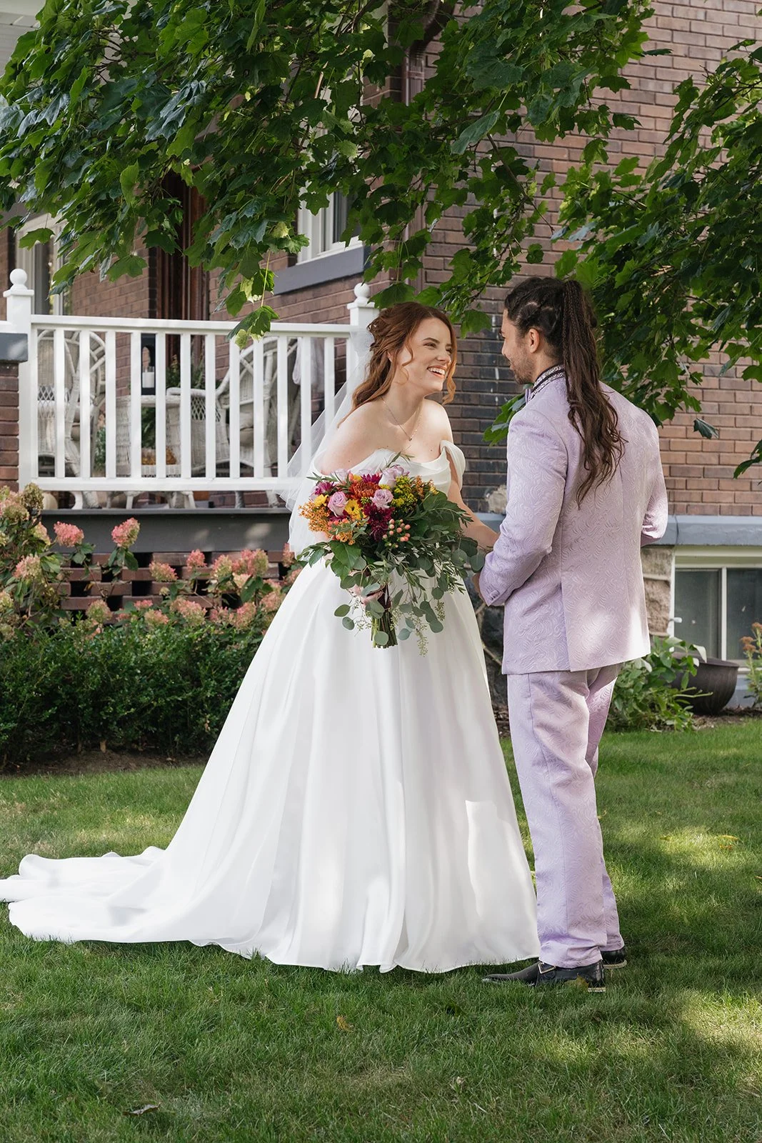 Bride and groom smiling during their first look outside of Brownstone Haus in Frankenmuth, Michigan.