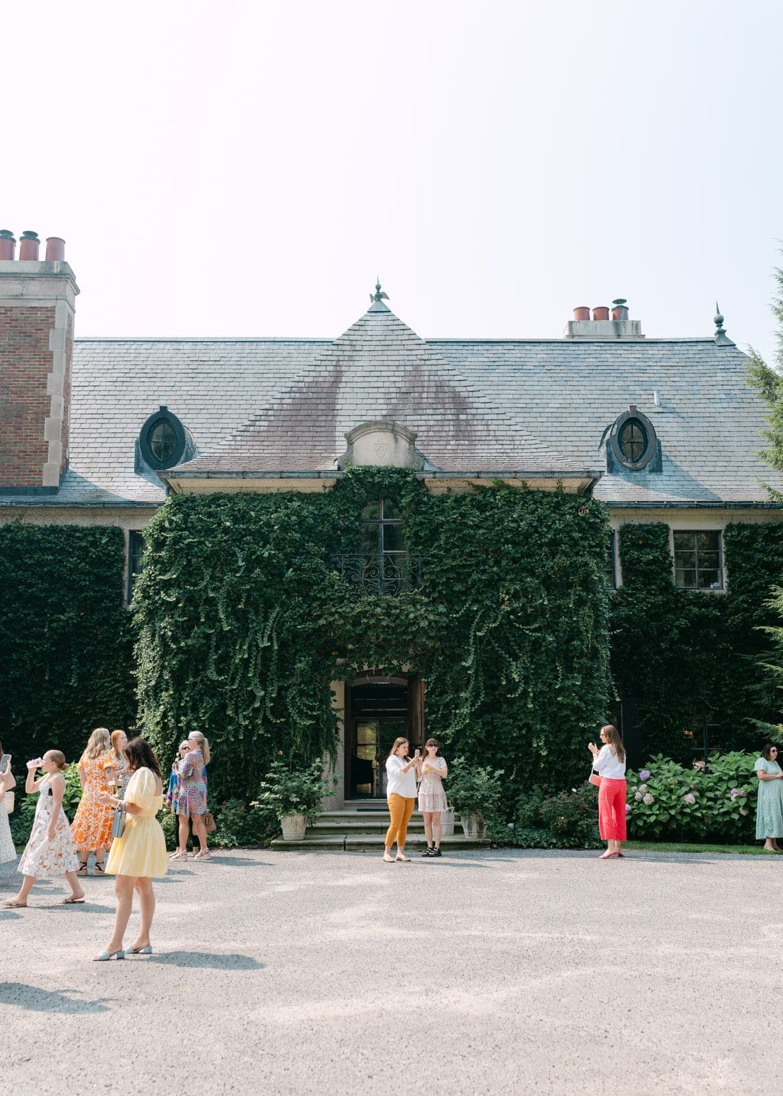 Cocktail hour at a Greencrest Manor wedding in Battle Creek, Michigan. The photo is of the front exterior of the French-inspired manor, covered in ivy.