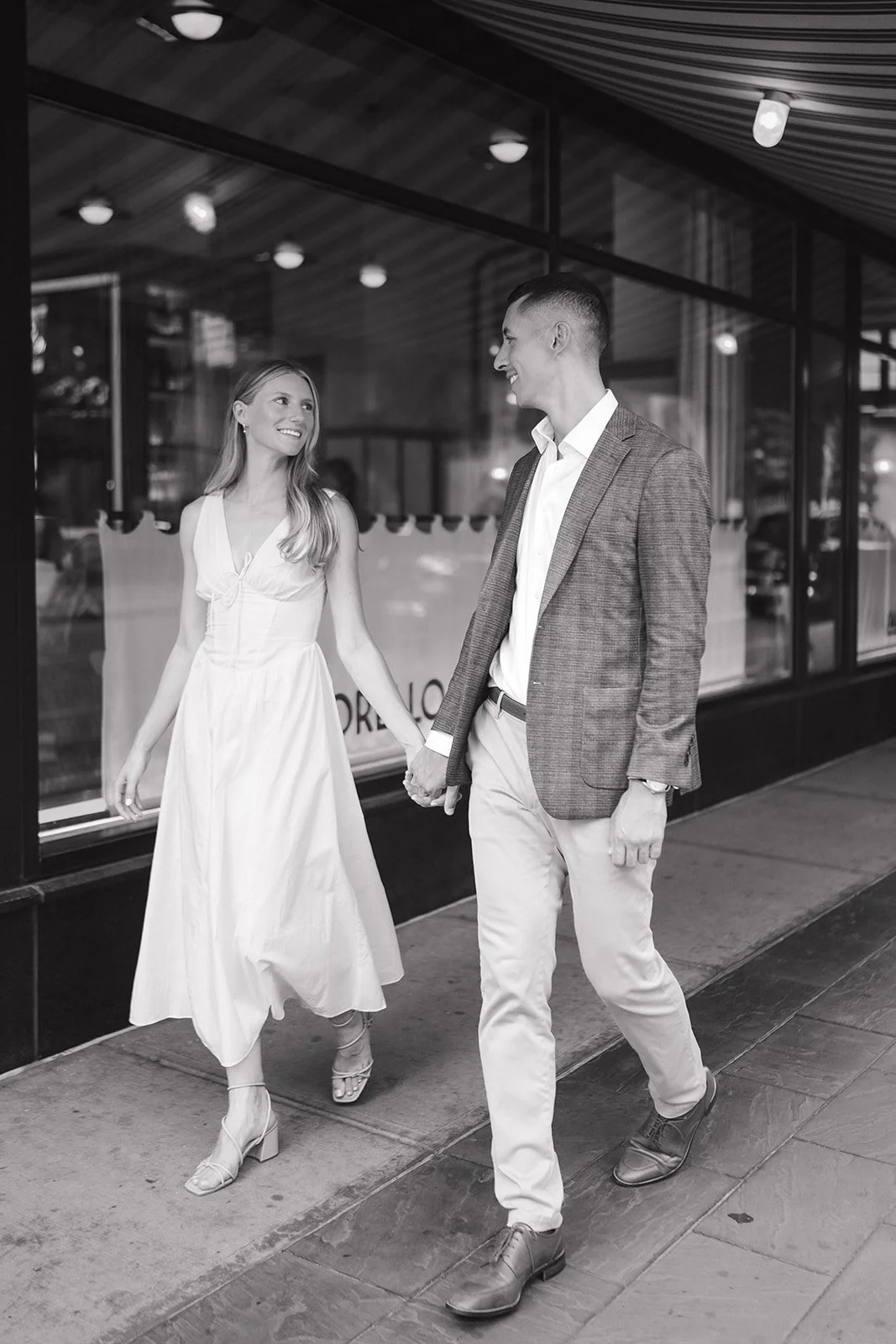 Black and white photo of a bride and groom walking downtown.