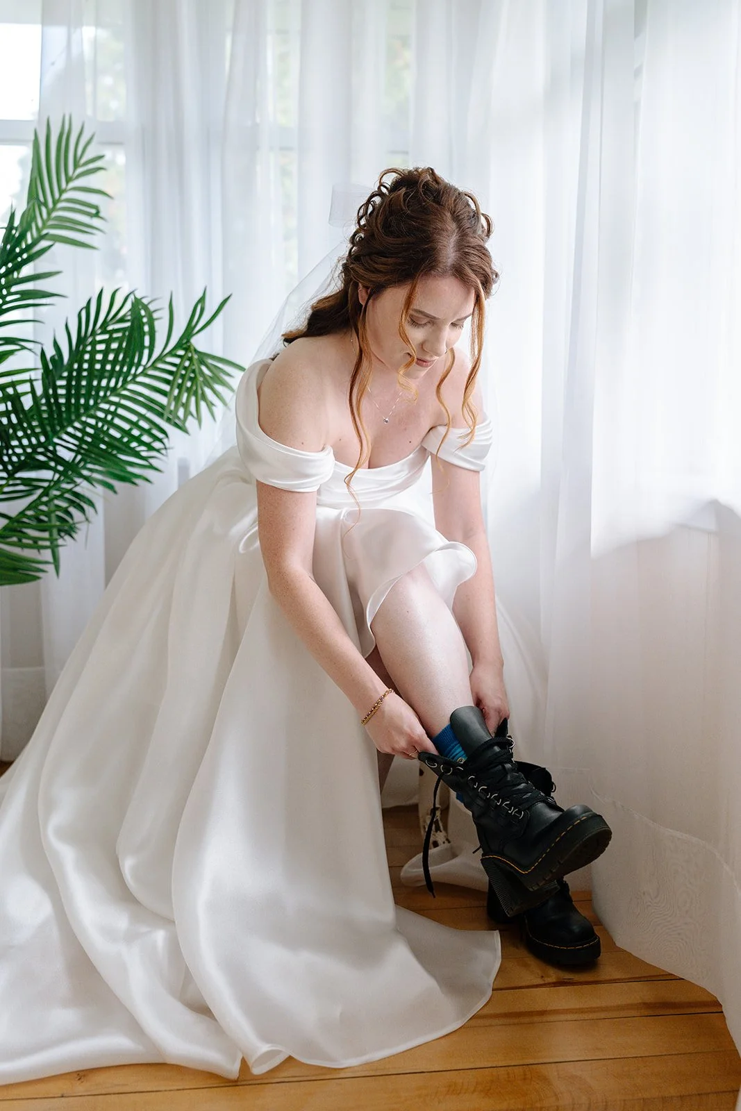 Bride putting her boots on as she gets ready at Brownstone Haus in Frankenmuth, Michigan.