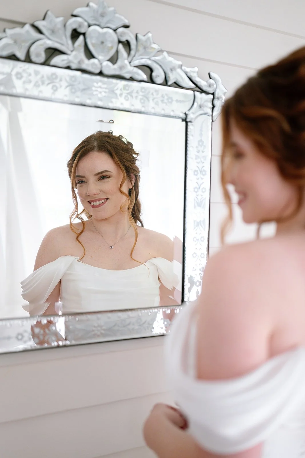 Bride smiling in the mirror as she gets ready at Brownstone Haus in Frankenmuth, Michigan.