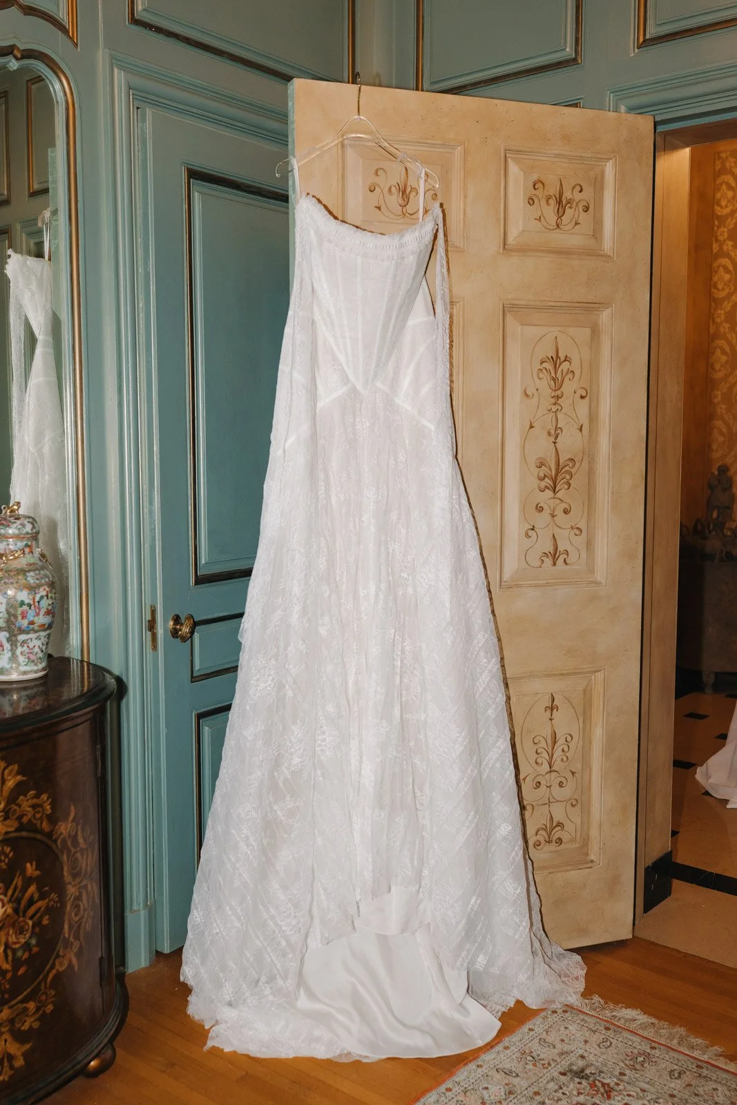An elegant lacy wedding dress hung over the ornate door at an estate wedding venue in Michigan.