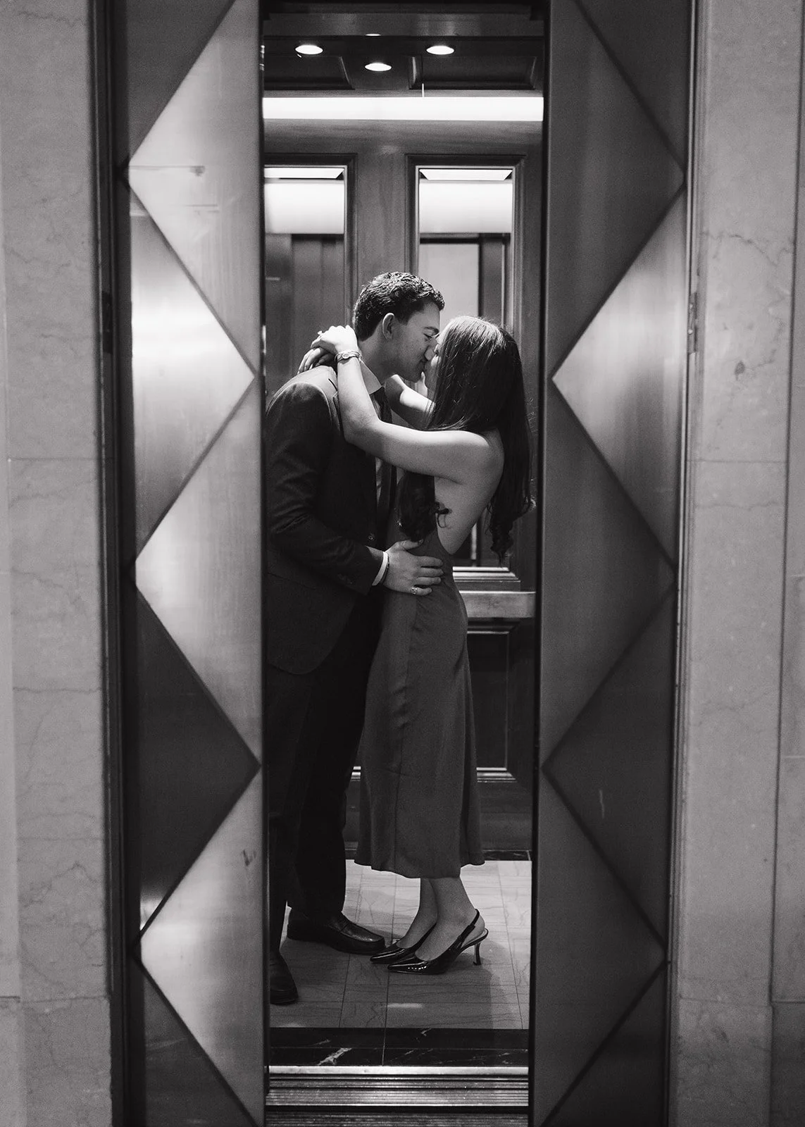 Black and white photo of a couple kissing inside the elevator at The Detroit Athletic Club for their Detroit engagement photos.
