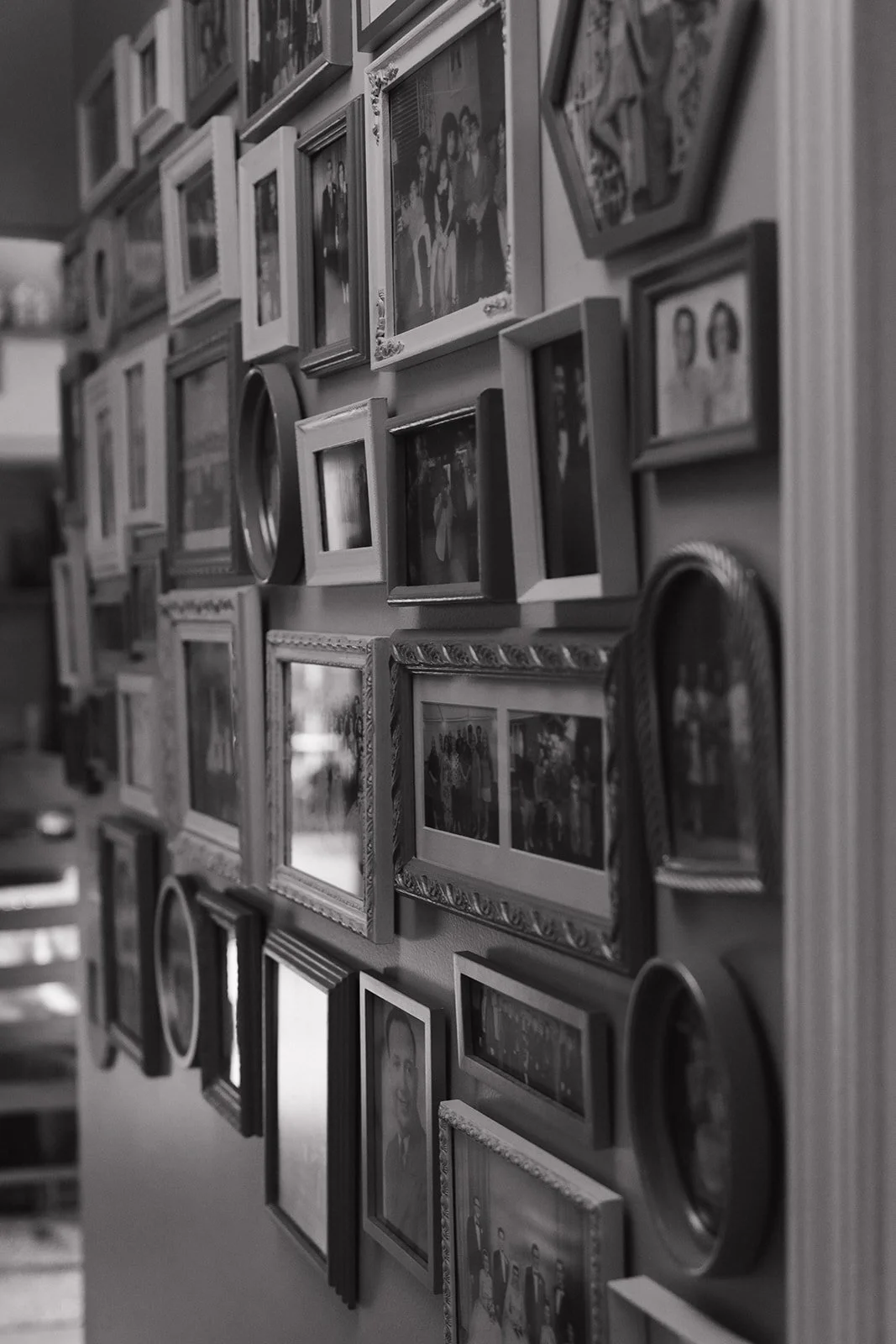 Black and white photo of family photos hanging on a wall.