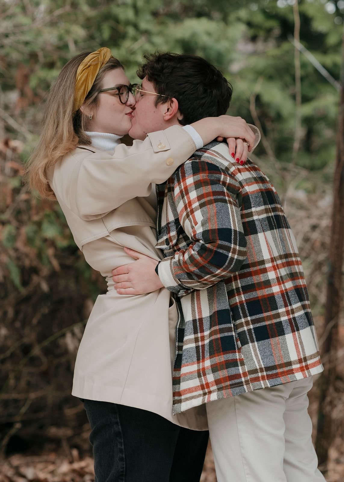 Couple kissing during engagement session in Ann Arbor park, wearing neutral tones and classic fall outfits