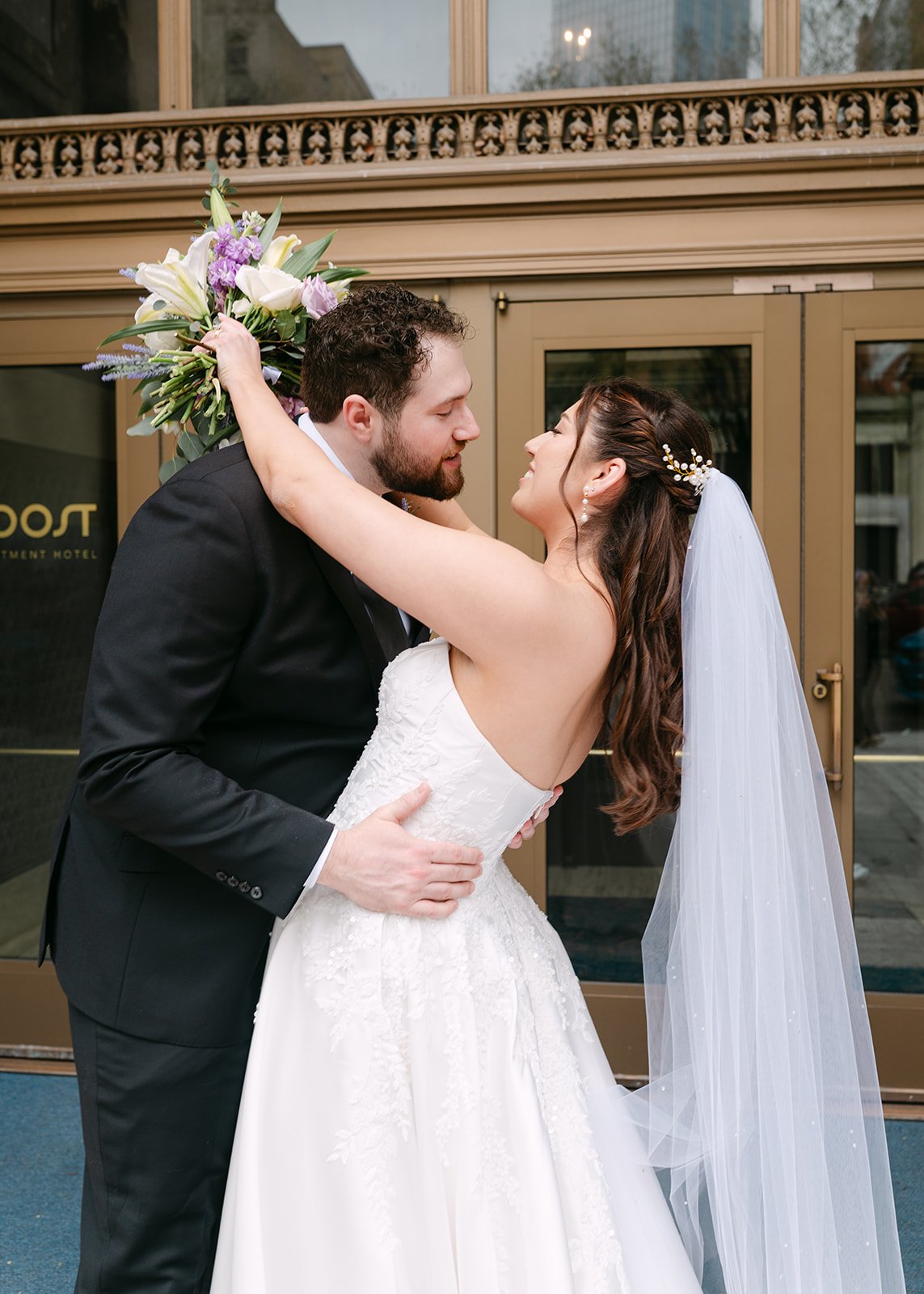 Bride and groom posing in front of the doors of ROOST Detroit for their Book Tower wedding.