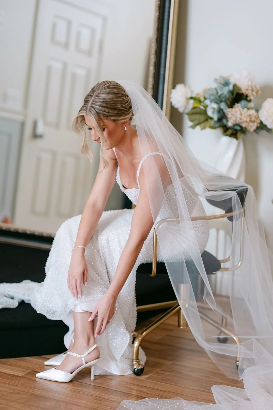 A bride lacing up her heels as she gets ready for her wedding ceremony.