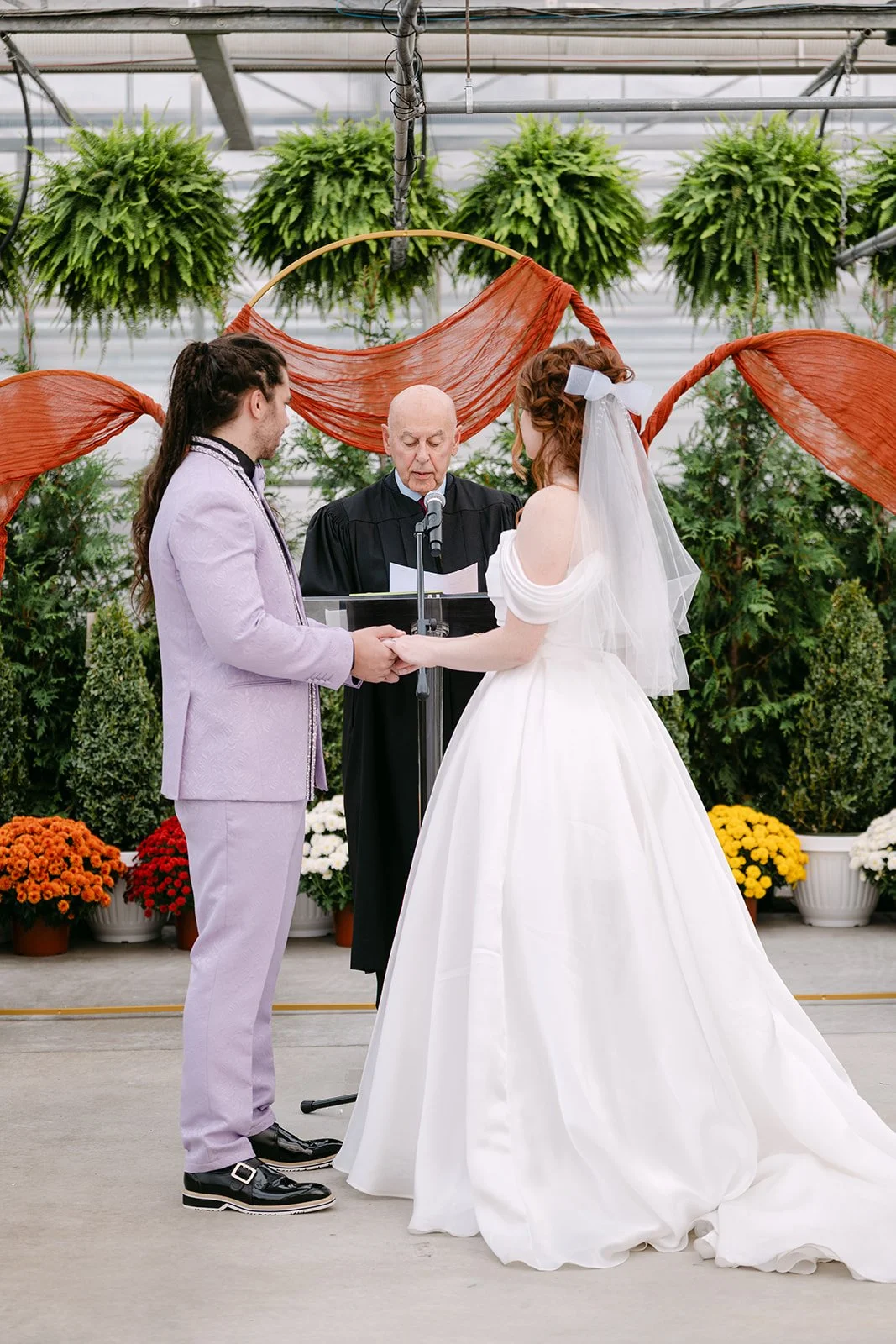 Bride and groom holding hands during Abele Greenhouse wedding ceremony in Saginaw, Michigan.