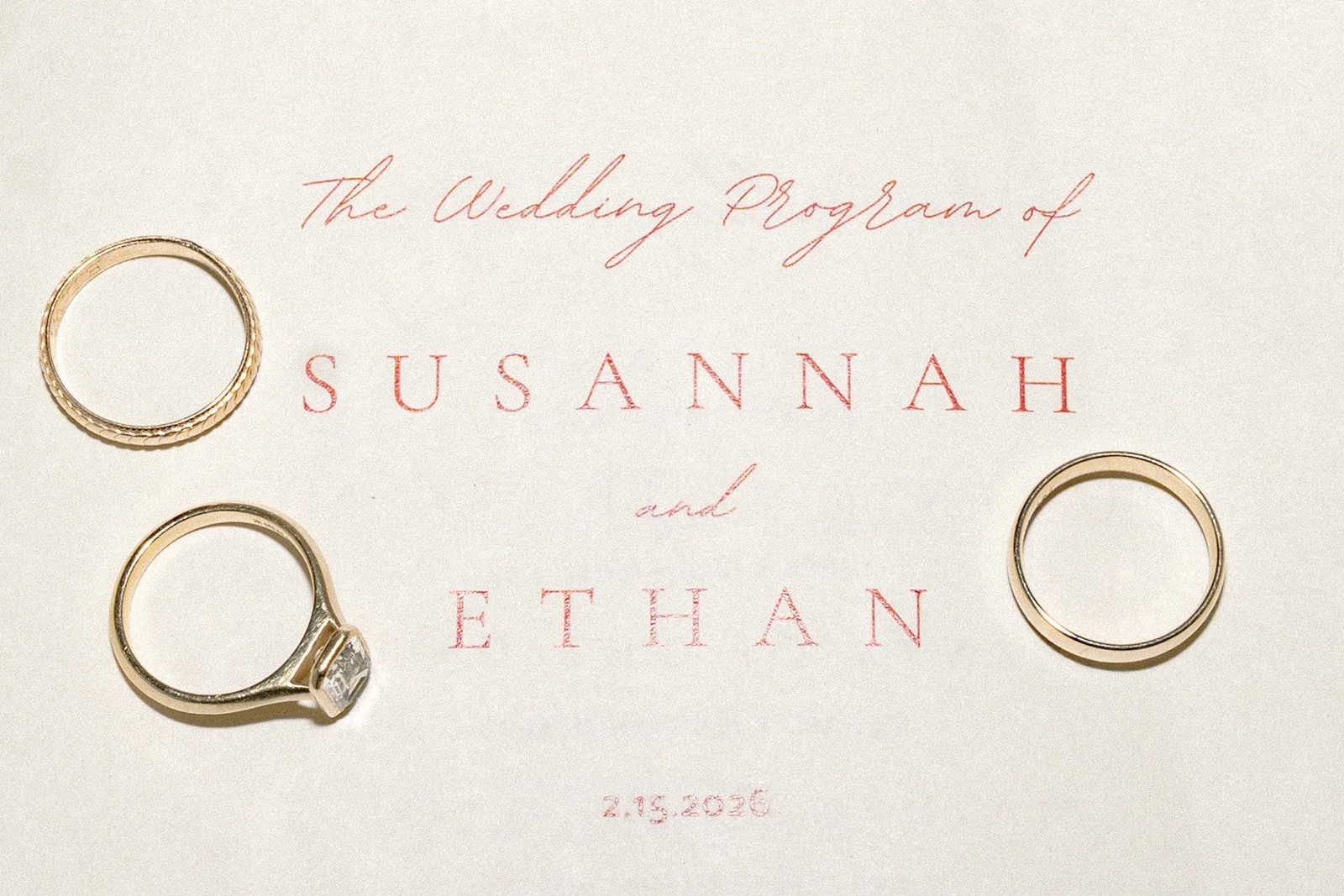 Close up wedding detail shot of the bride and grooms invite with rings and wedding band styled on top.