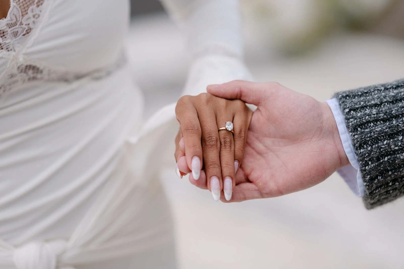 Couple holding hands during their Detroit engagement photos while showing off an engagement ring.