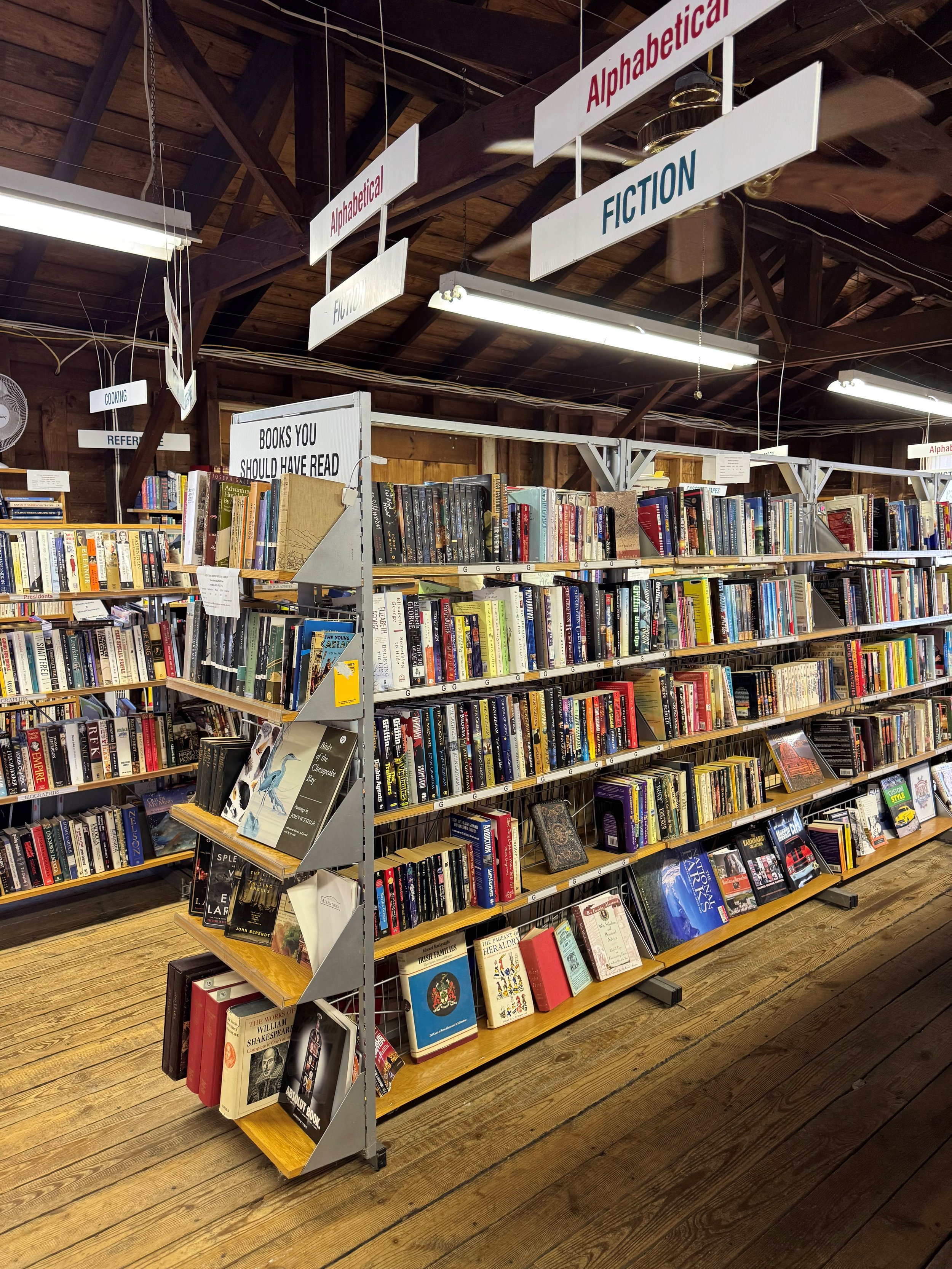 Stacked books of various sizes, colors, and titles, arranged vertically on a shelf.