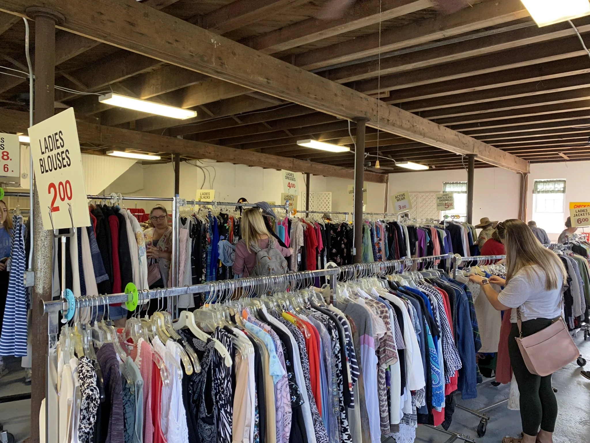 Clothing rack with various colorful dresses and shirts on hangers.