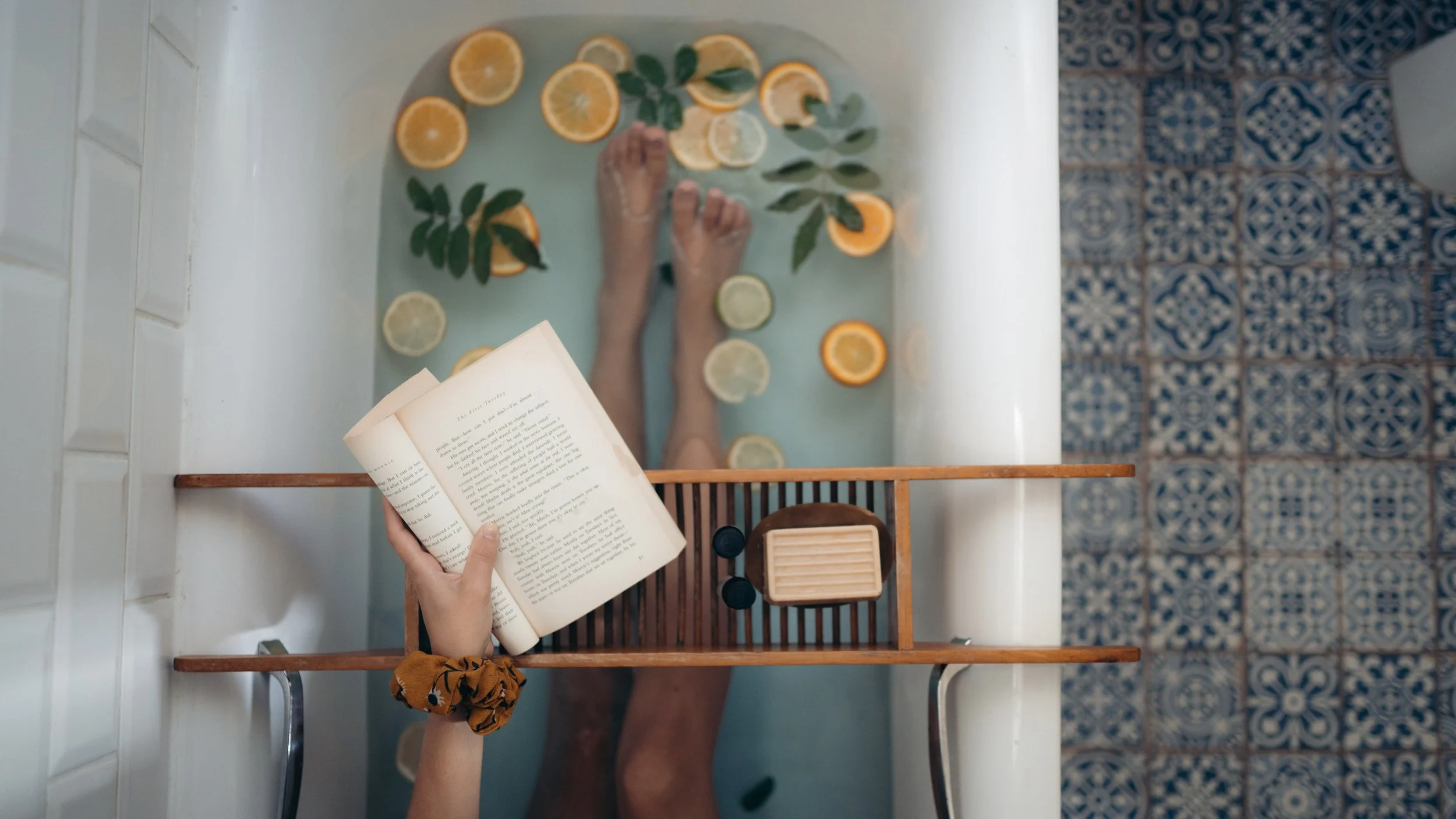 Woman relaxing in a bathtub and reading a book