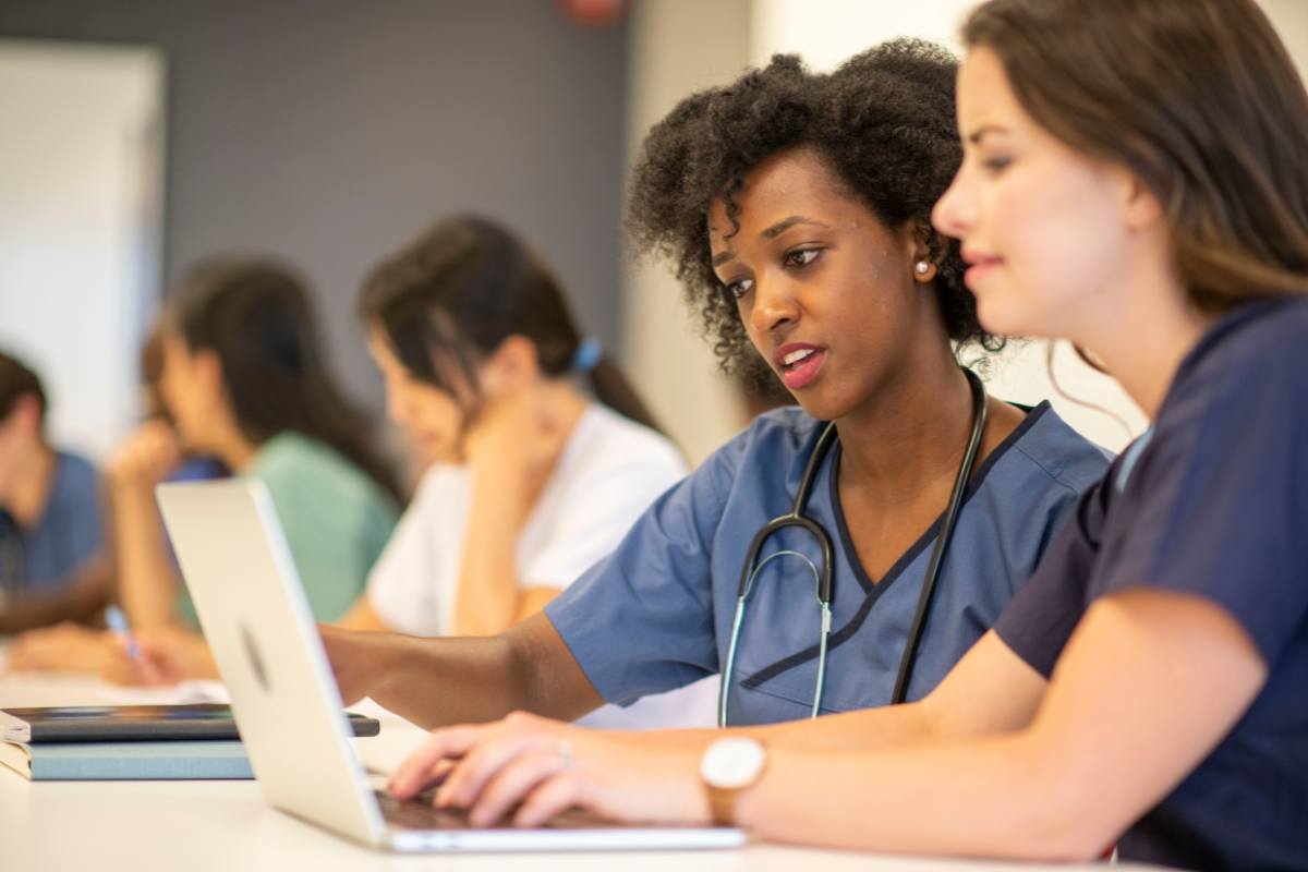 Two nurses on a laptop looking for resources