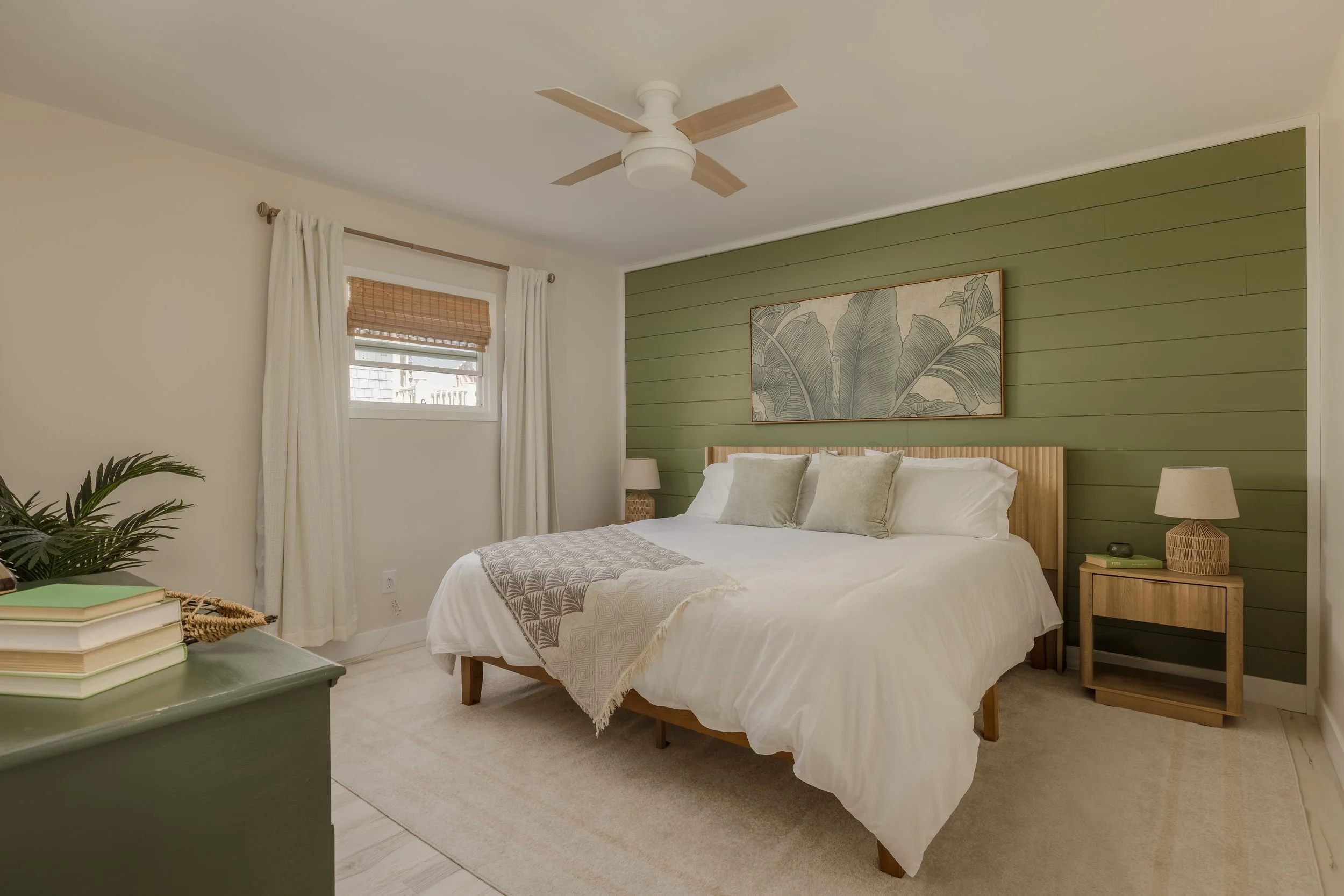 Palm tree bedroom with wood headboard, green shiplap, palm art, bamboo blinds