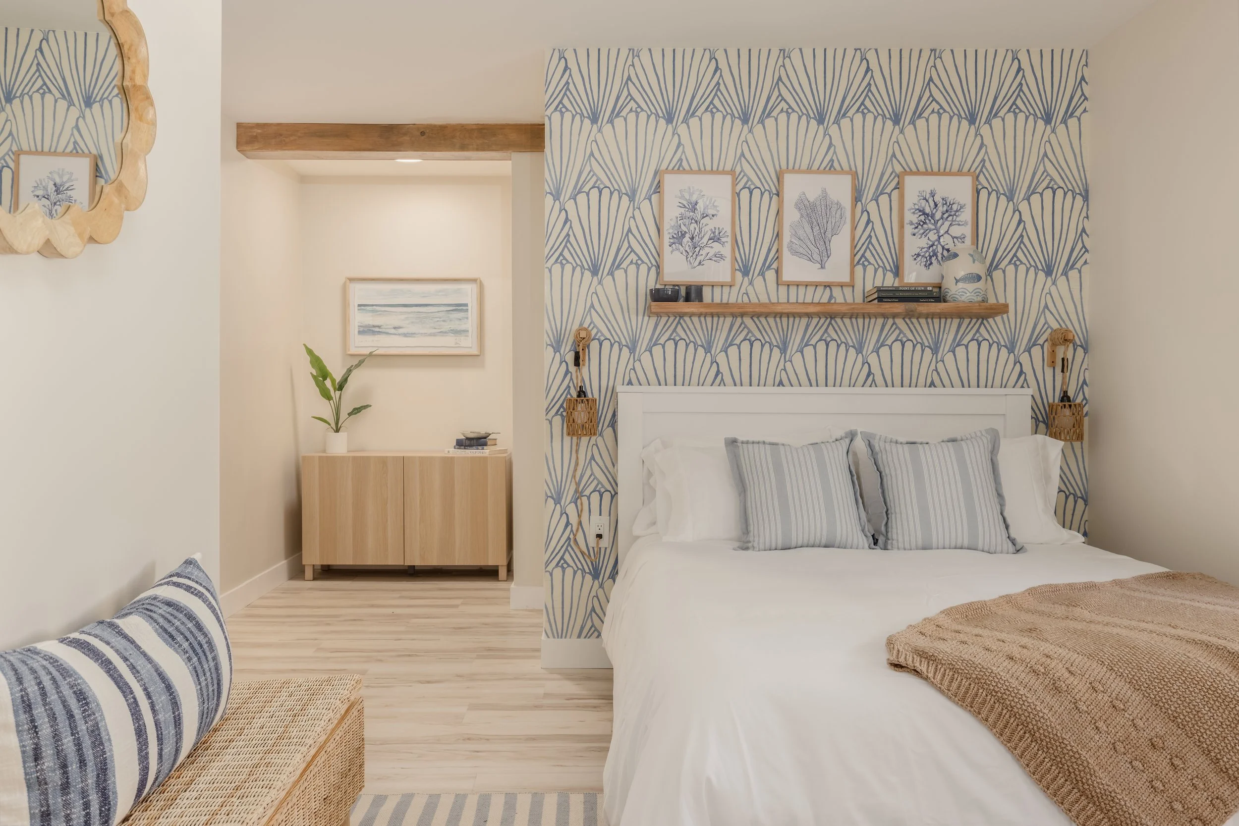 Ocean themed bedroom with shell wall paper, ocean art, watercolor art, blue striped rugs and pillows