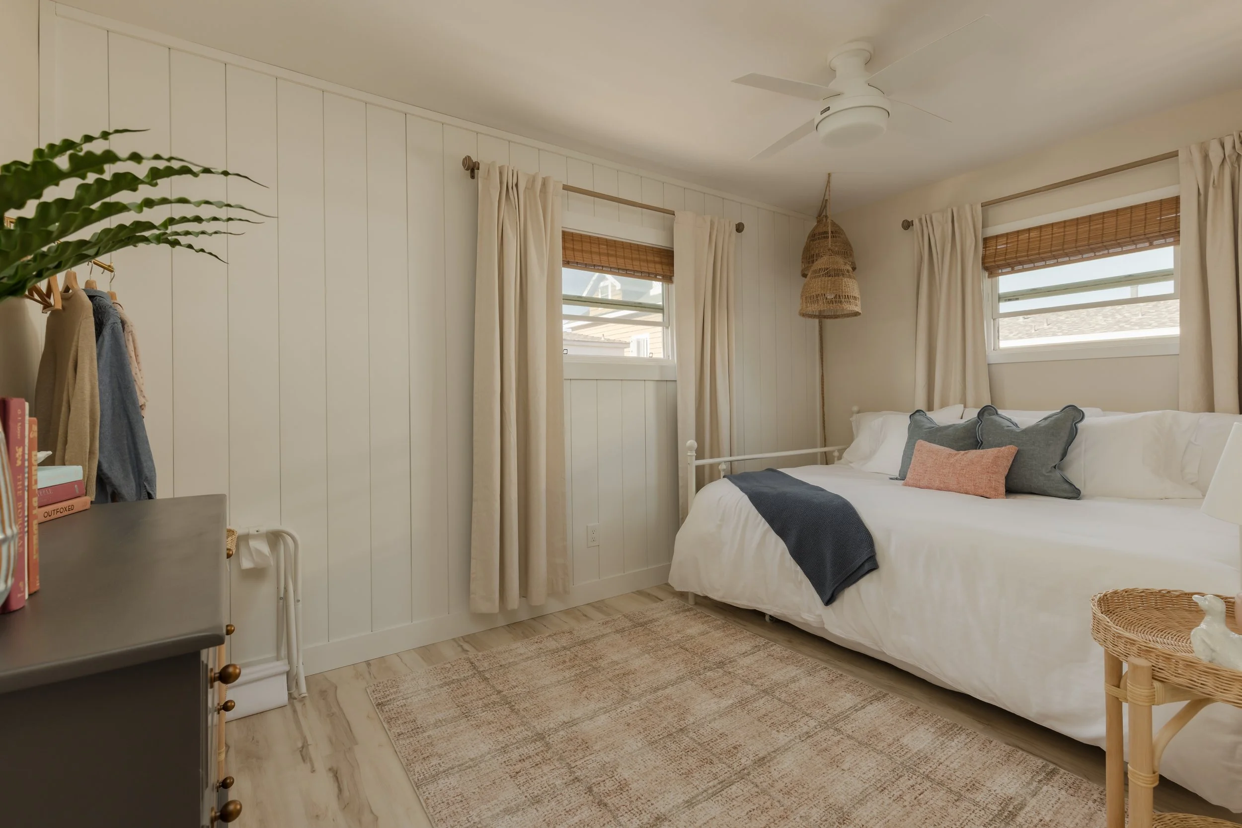 Sunset themed bedroom with bamboo blinds, white shiplap, trundle bed, blue and pink pillows