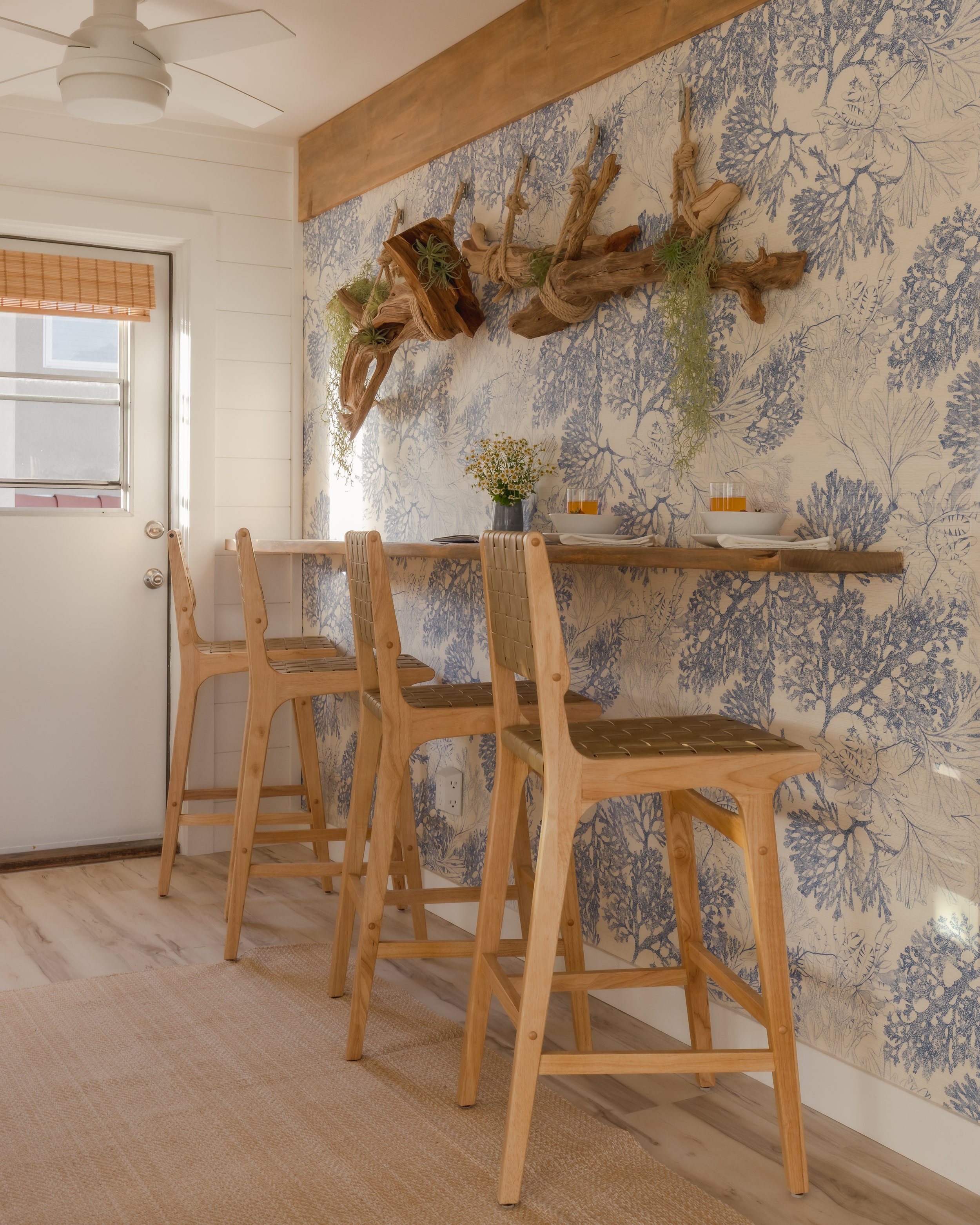 Photograph of the interior design and decorating of a rental unit with driftwood, bar seating, and ocean themed wallpaper