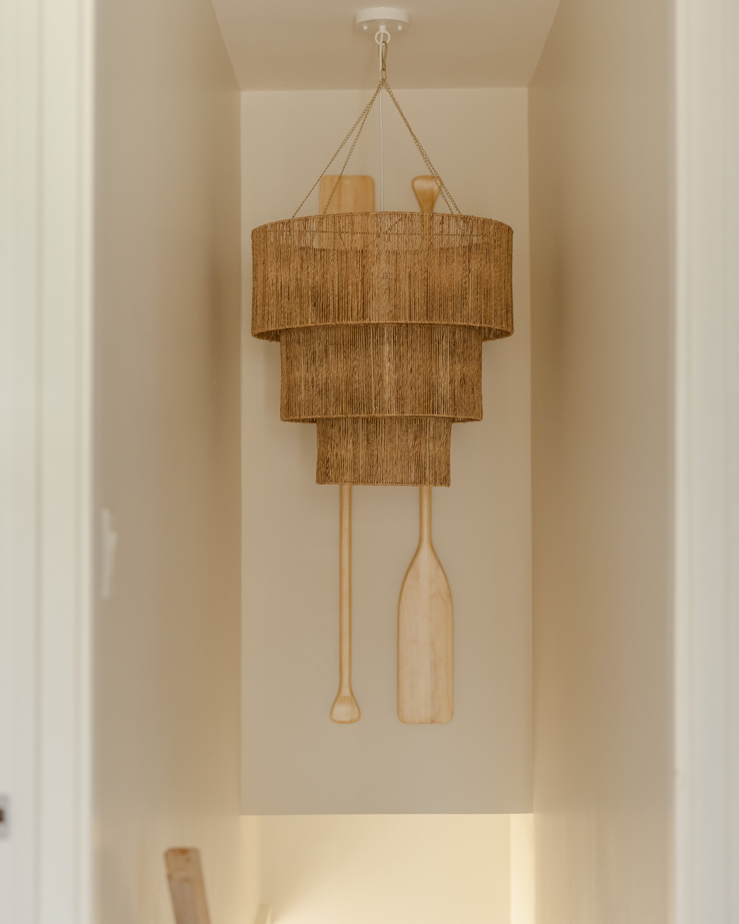 Photograph of the interior design and decorating of a coastal hallway with a chandelier and wood boat oars