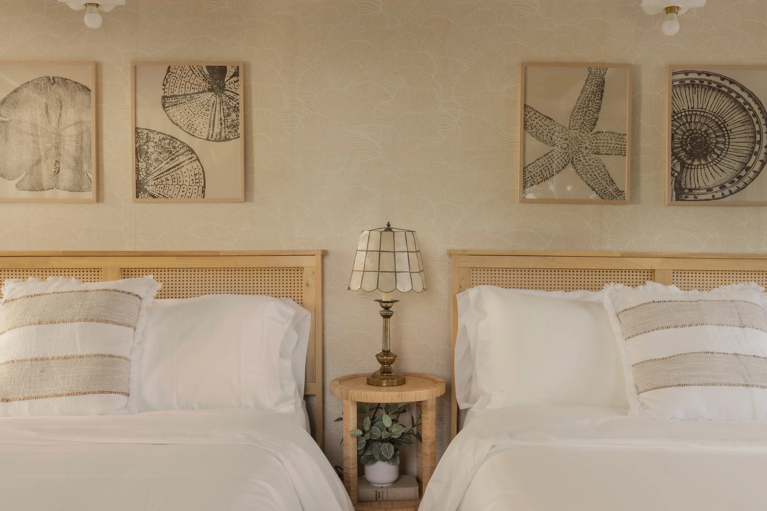 Photograph of a seashell bedroom with rattan night stand, coastal art, thrifted lamp
