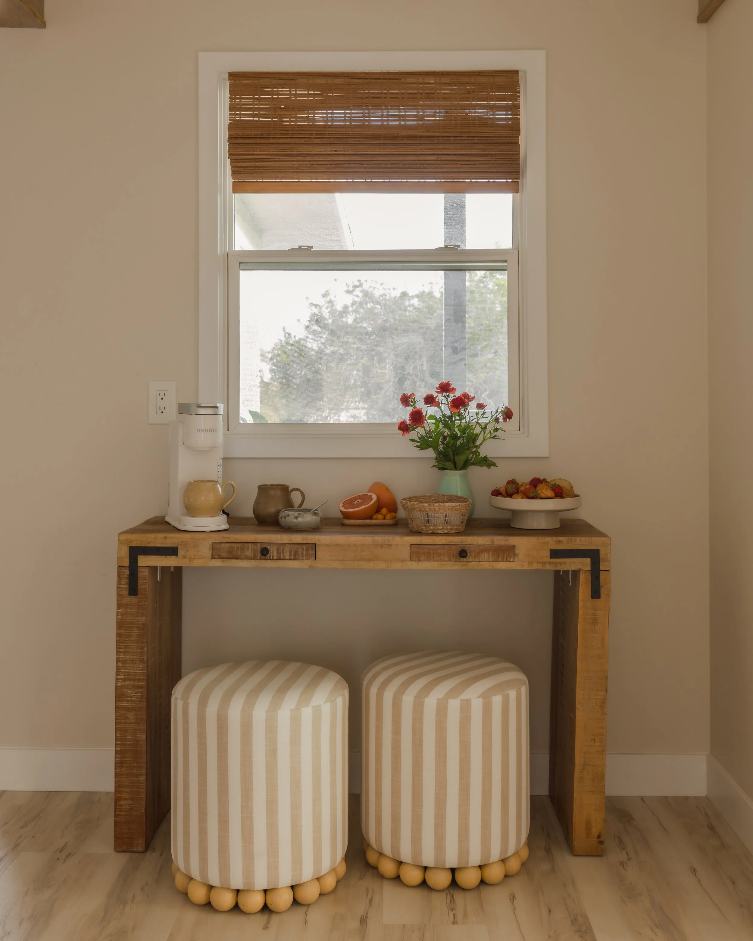 Photograph of the interior design and decorating of a coastal coffee bar with striped ottomans and bamboo blinds.