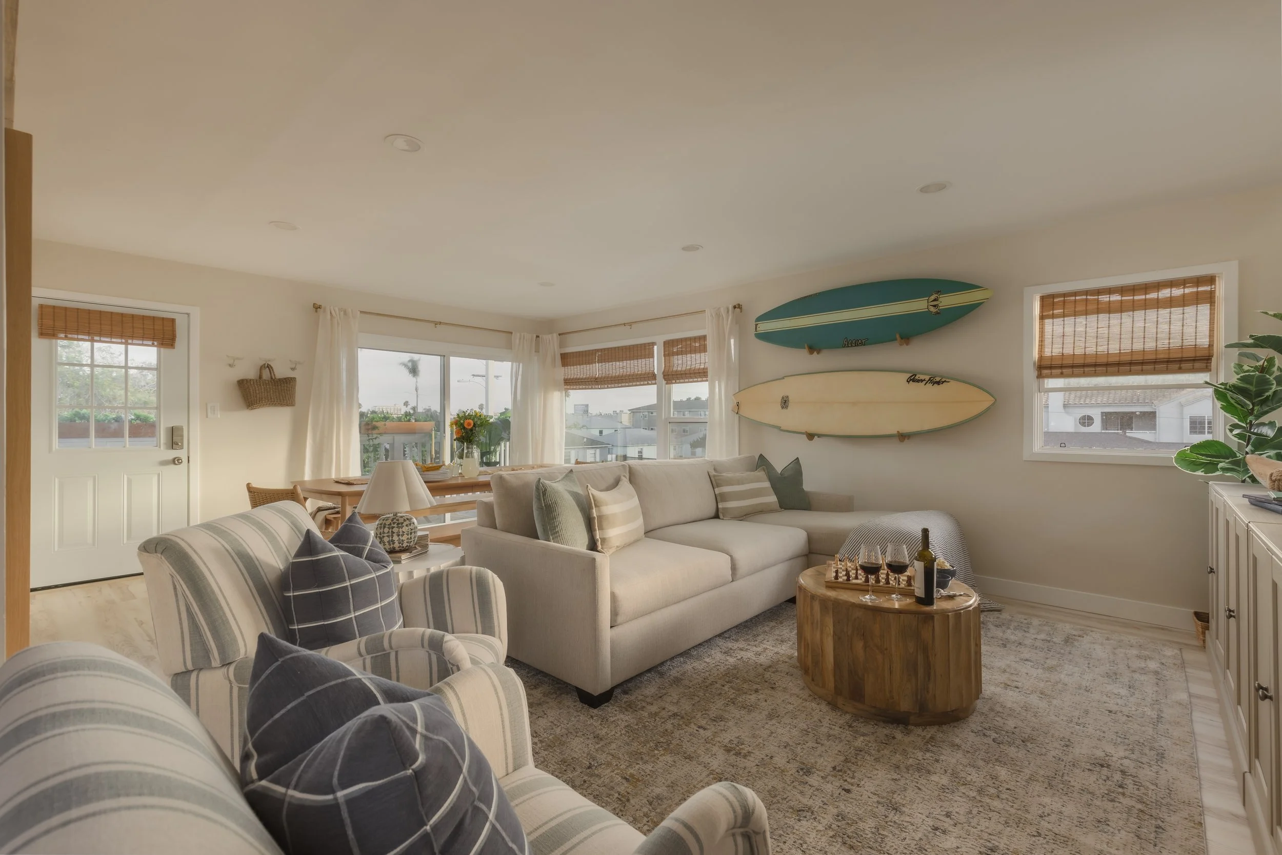 Photograph of the interior design and decorating of a coastal living room with striped chairs and surfboards