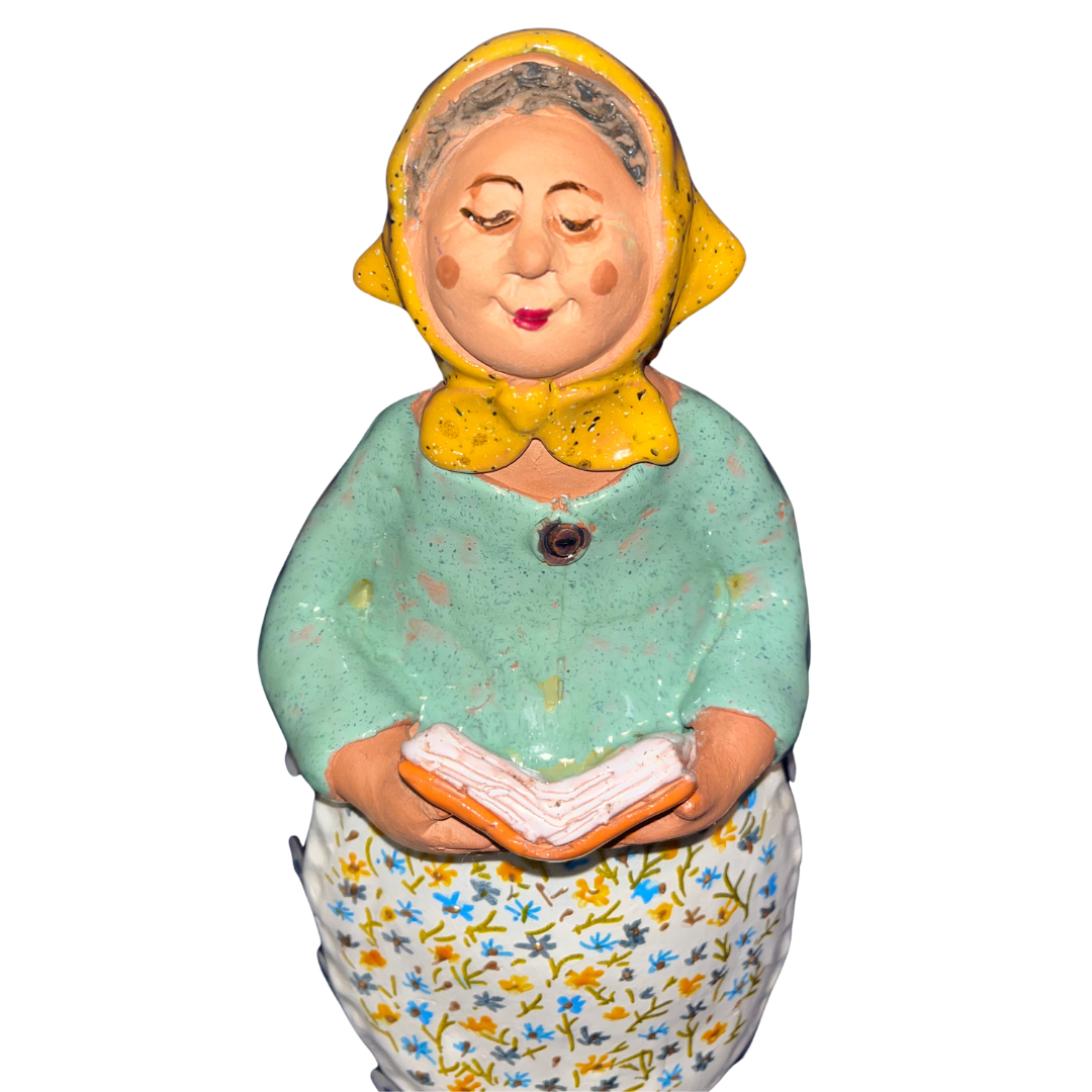 Charming hand-painted “Babcia Holding a Book” figurine featuring a Polish grandmother in an aqua scarf and floral apron. A heartwarming gift and beautiful piece of folk-inspired home décor.
