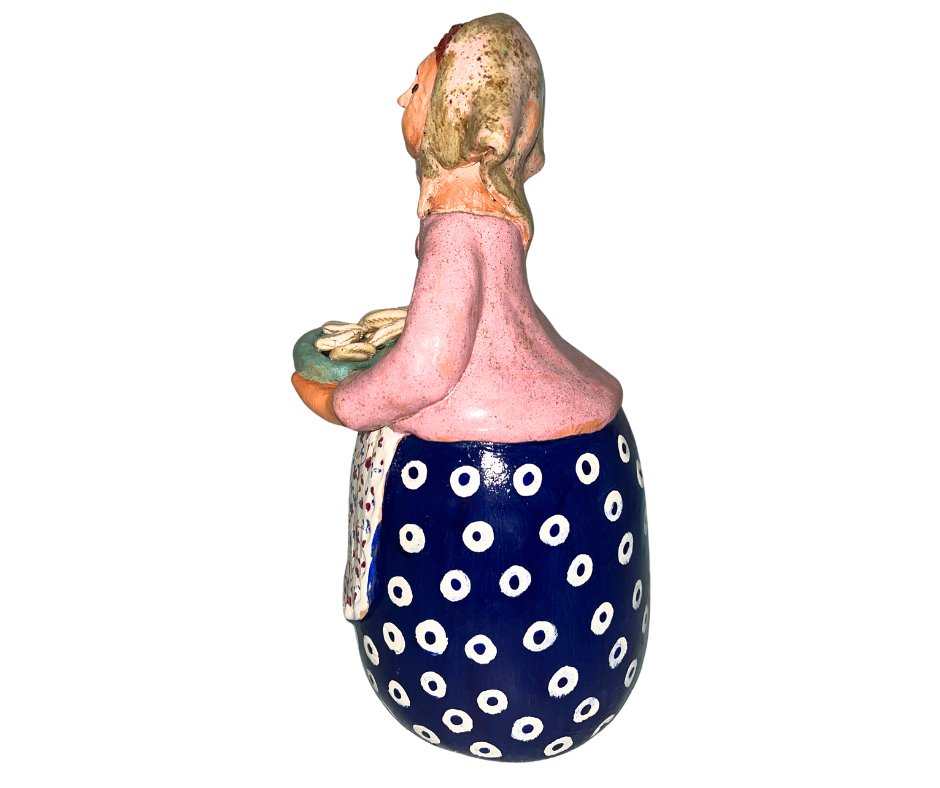 Hand-painted babcia figurine holding a bowl of pierogi, wearing a tan scarf and floral apron