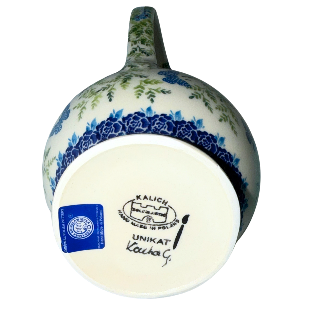 Ceramika Kalich Polish Pottery 37 oz Kubus pitcher with blue and white flowers, green foliage and butterflies, handcrafted in Bolesławiec, Poland.