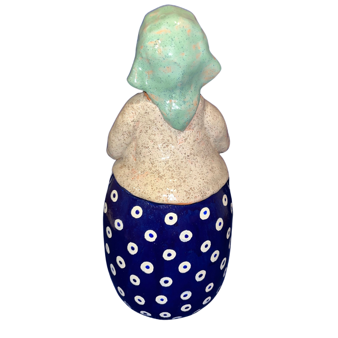Charming hand-painted “Babcia Holding a Book” figurine featuring a Polish grandmother in an aqua scarf and floral apron. A heartwarming gift and beautiful piece of folk-inspired home décor.