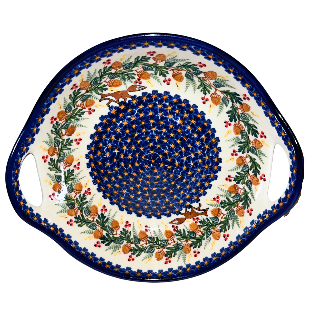 Celebrate the beauty of autumn with this enchanting Kalich Polish Pottery bowl with handles in pattern 446 featuring playful foxes, oak leaves, golden acorns, and clusters of red berries.