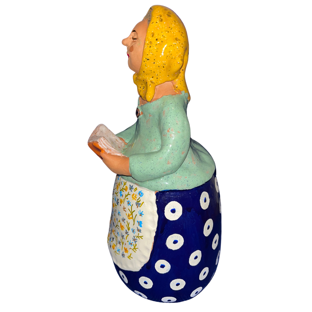 Charming hand-painted “Babcia Holding a Book” figurine featuring a Polish grandmother in an aqua scarf and floral apron. A heartwarming gift and beautiful piece of folk-inspired home décor.