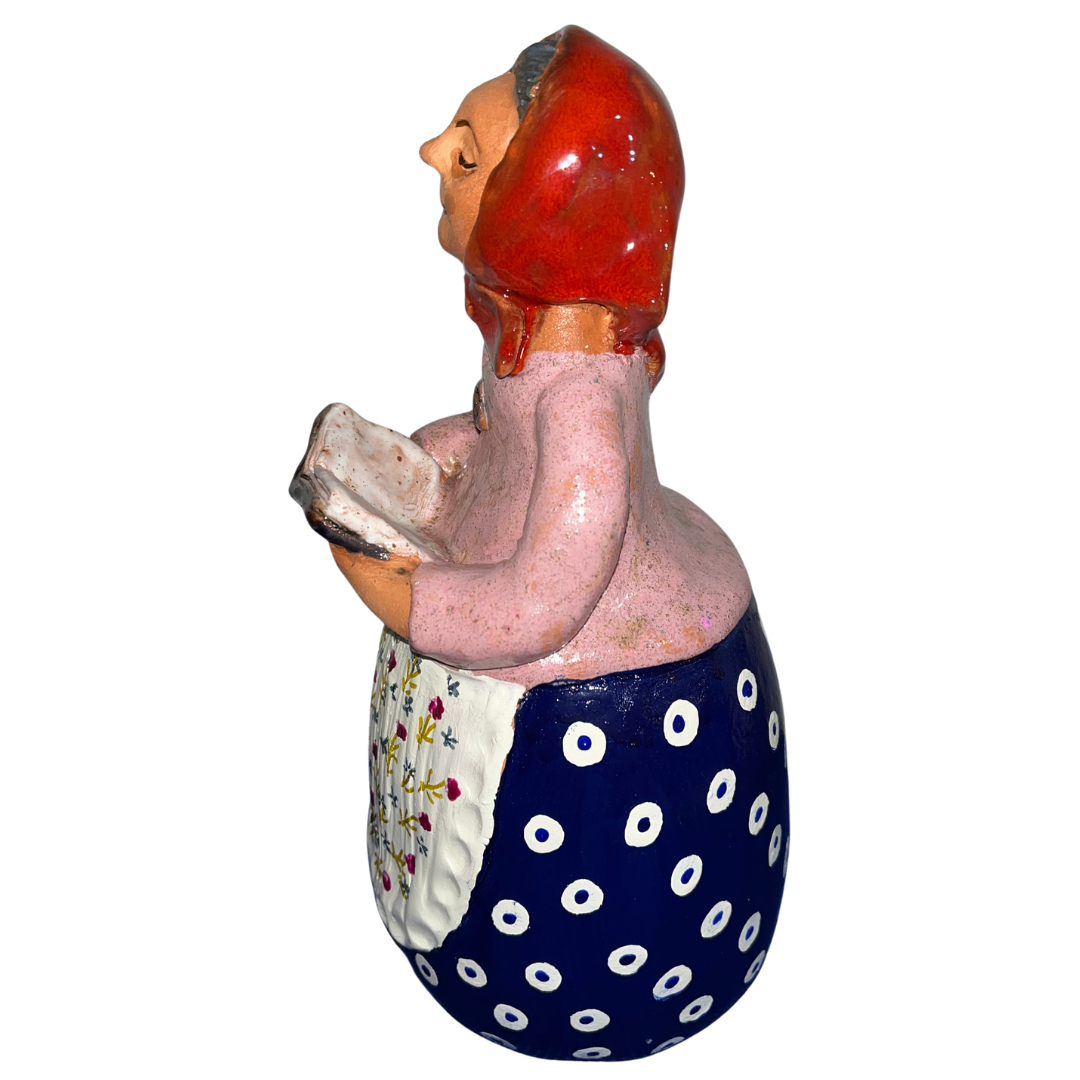 Charming hand-painted “Babcia Holding a Book” figurine featuring a Polish grandmother in an aqua scarf and floral apron. A heartwarming gift and beautiful piece of folk-inspired home décor.