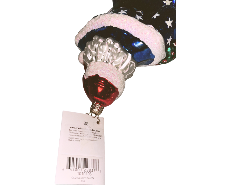 Patriotic Santa in starry blue coat and striped robe with wreath. Handcrafted, hand-painted Christopher Radko glass ornament made in Poland — festive American spirit.