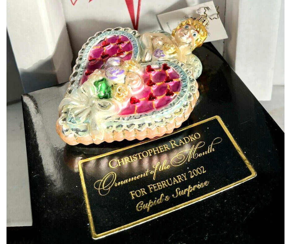Christopher Radko Cupid’s Surprise ornament—hand-painted glass cherub with pink heart and flowers. Made in Poland, perfect for collectors and holiday romantics.