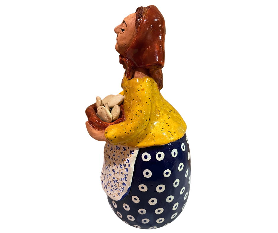 Hand-painted babcia figurine holding a bowl of pierogi, wearing a red scarf and floral apron