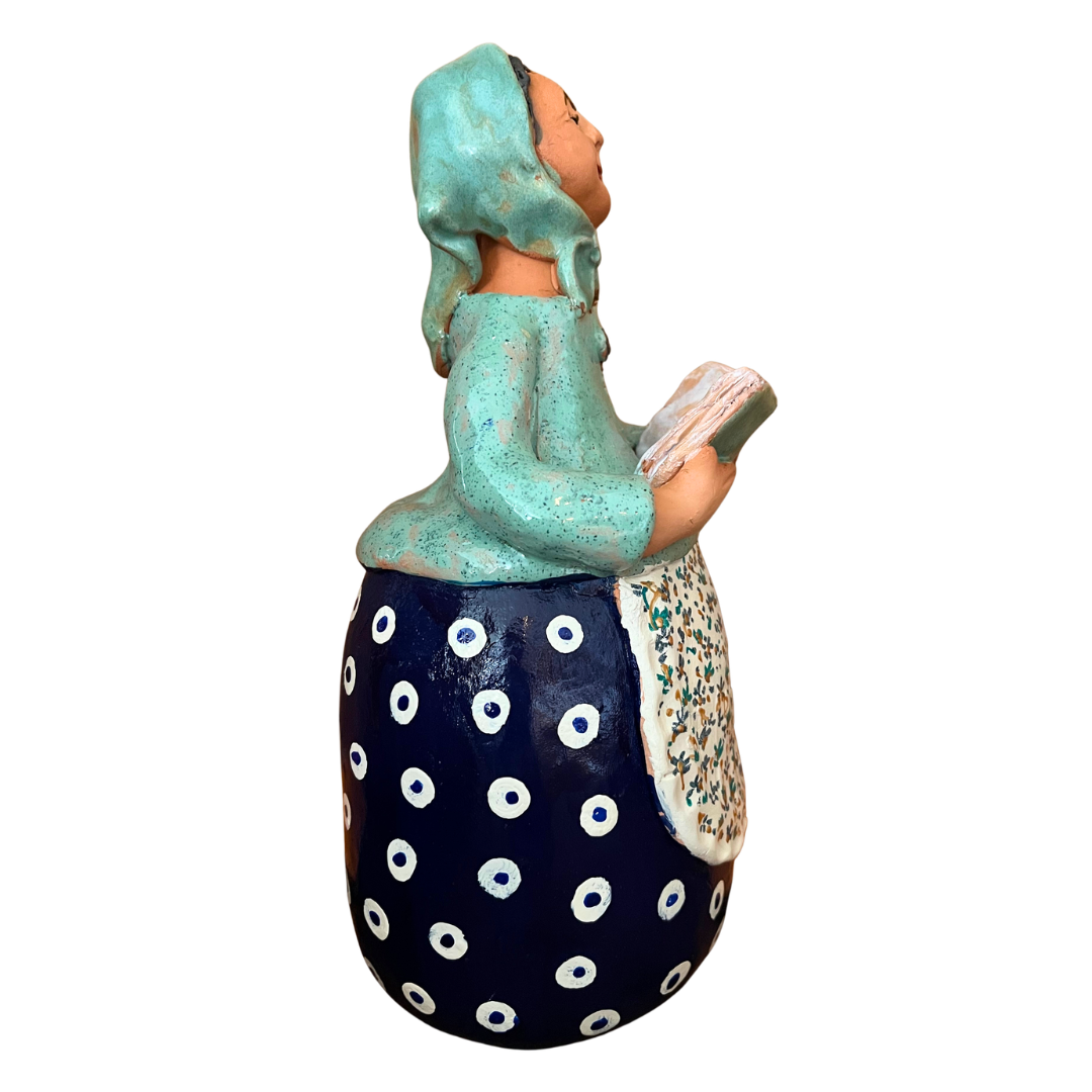 Charming hand-painted “Babcia Holding a Book” figurine featuring a Polish grandmother in an aqua scarf and floral apron. A heartwarming gift and beautiful piece of folk-inspired home décor.