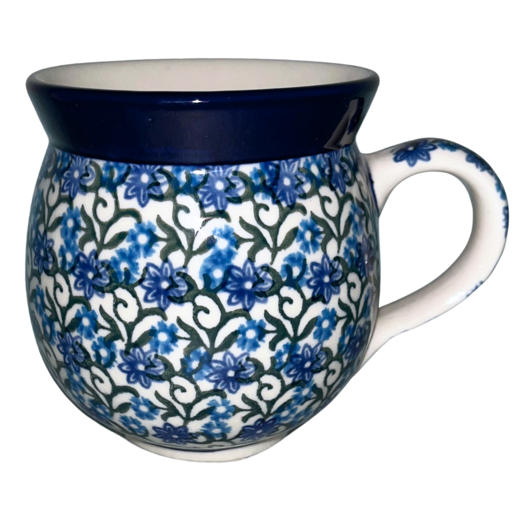 Ceramika Artystyczna Pattern 1459X Daisy Lace features blue daisy blossoms, scrolling green vines, and a cobalt rim. Handcrafted Polish pottery from Bolesławiec, Poland.