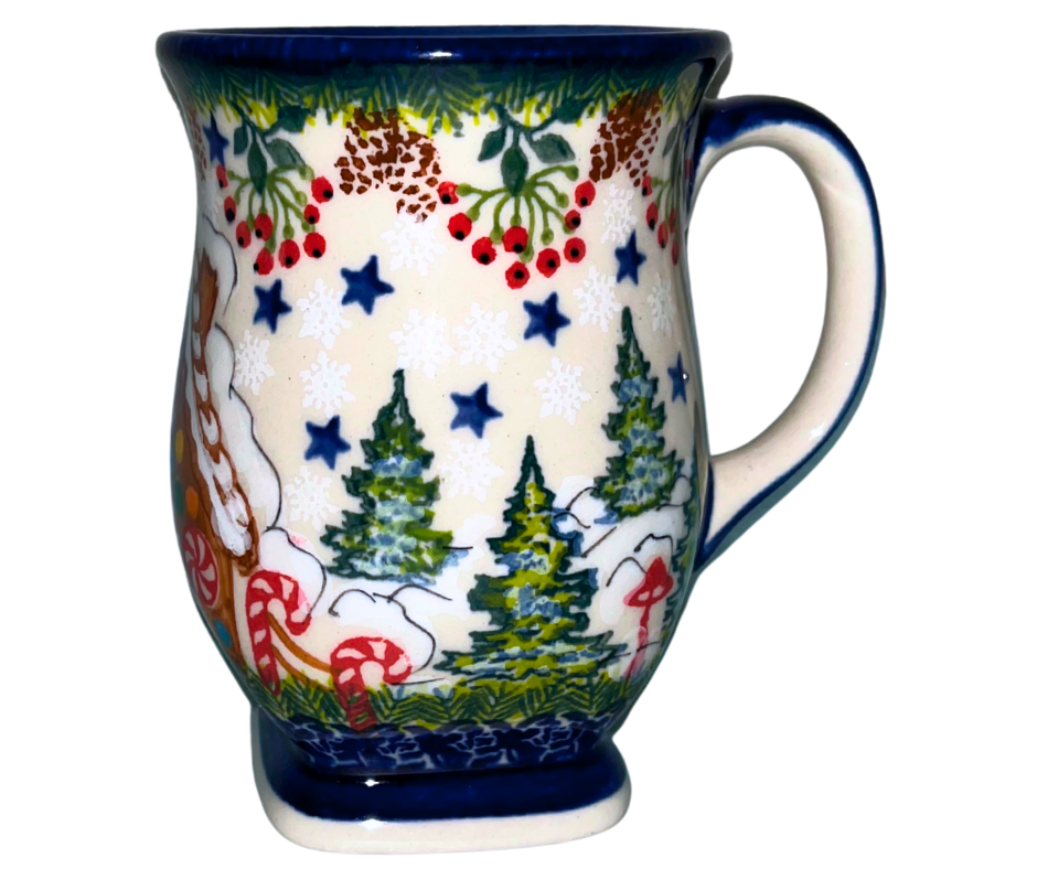 Hand-painted ceramic mug featuring a festive gingerbread cottage surrounded by evergreen branches, berries, and holiday stars. Durable, functional art—perfect for coffee, tea, or seasonal gifting.