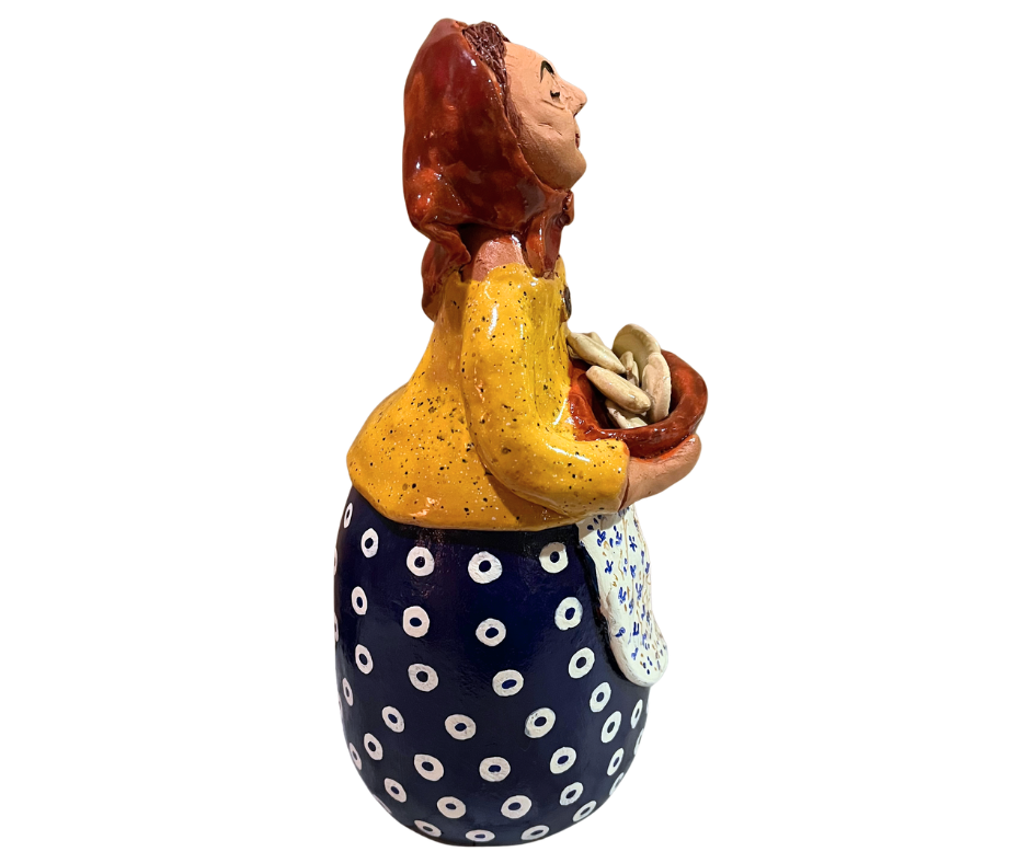 Hand-painted babcia figurine holding a bowl of pierogi, wearing a red scarf and floral apron