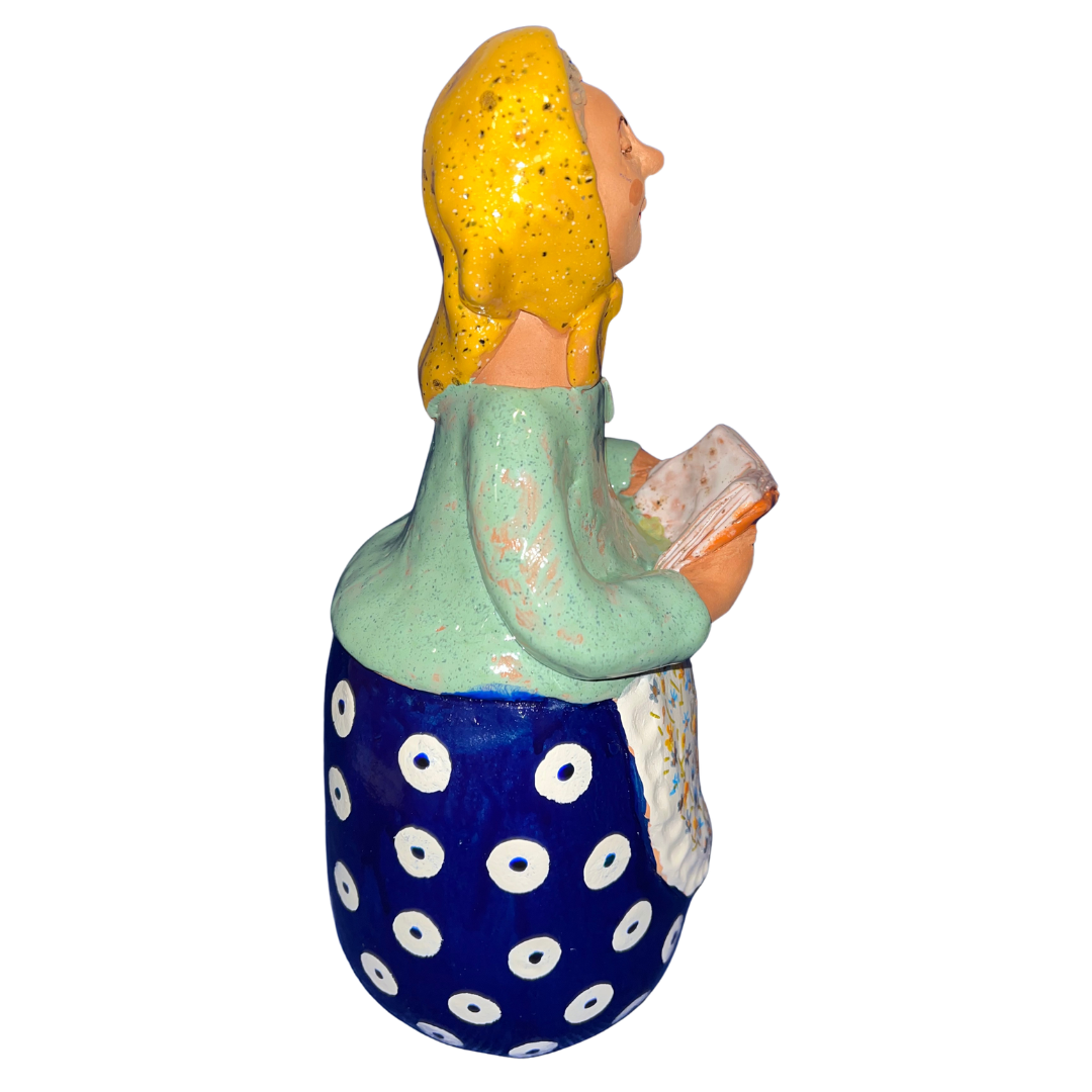 Charming hand-painted “Babcia Holding a Book” figurine featuring a Polish grandmother in an aqua scarf and floral apron. A heartwarming gift and beautiful piece of folk-inspired home décor.