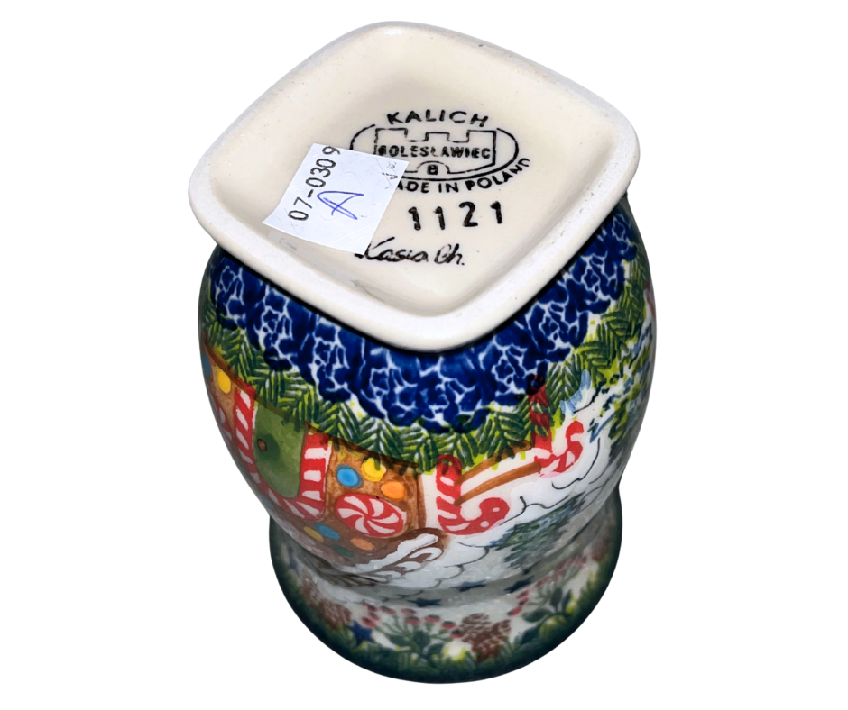 Hand-painted ceramic mug featuring a festive gingerbread cottage surrounded by evergreen branches, berries, and holiday stars. Durable, functional art—perfect for coffee, tea, or seasonal gifting.