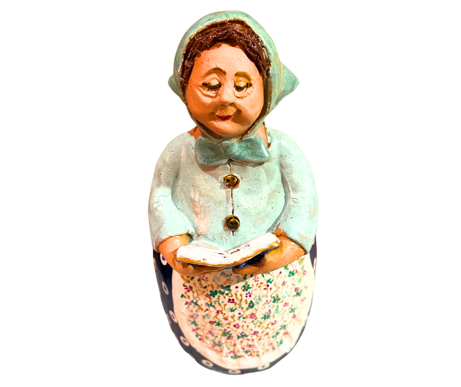 Charming hand-painted “Babcia Holding a Book” figurine featuring a Polish grandmother in an aqua scarf and floral apron. A heartwarming gift and beautiful piece of folk-inspired home décor.