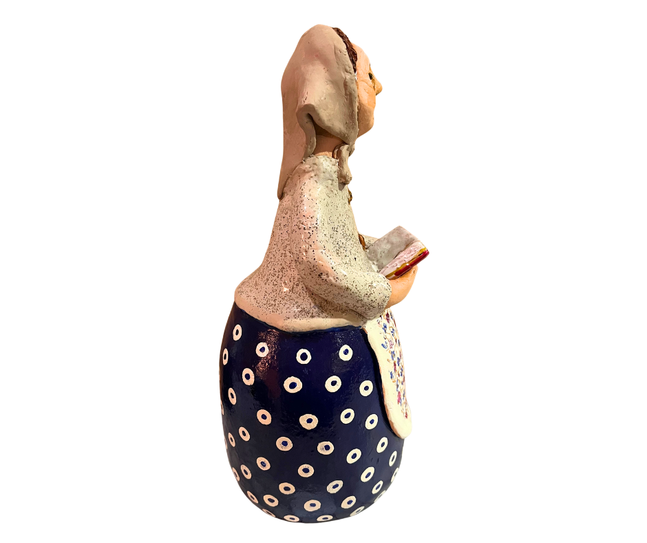 Charming hand-painted “Babcia Holding a Book” figurine featuring a Polish grandmother in an aqua scarf and floral apron. A heartwarming gift and beautiful piece of folk-inspired home décor.