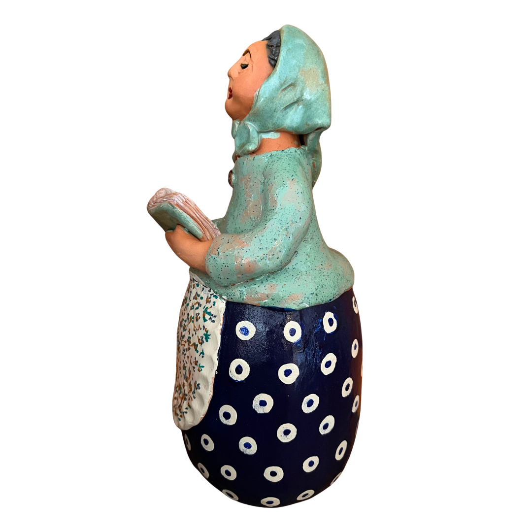Charming hand-painted “Babcia Holding a Book” figurine featuring a Polish grandmother in an aqua scarf and floral apron. A heartwarming gift and beautiful piece of folk-inspired home décor.