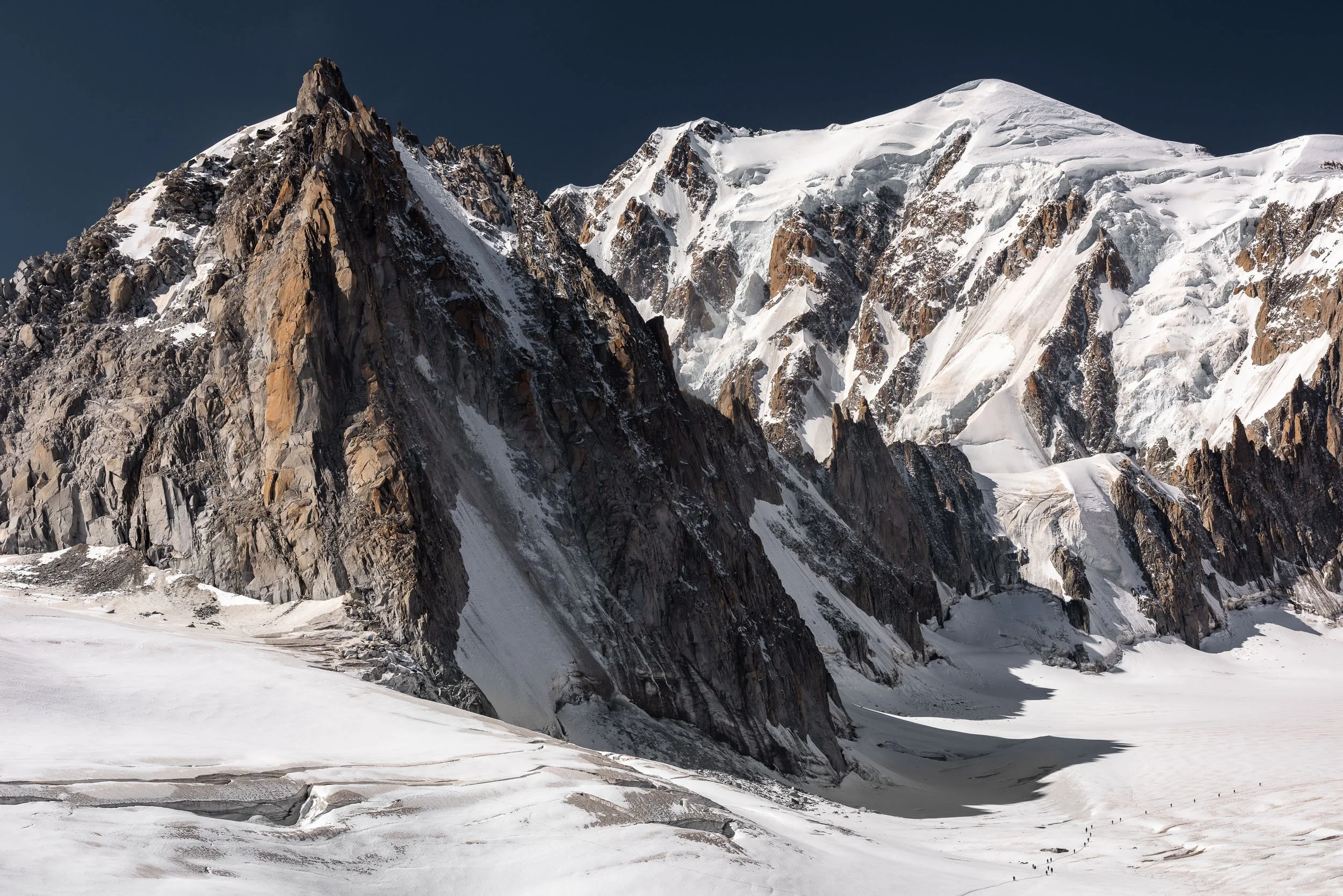 Mountaineers traverse a crevassed Glacier du Géant beneath Tour Ronde, L'arête de la Brenva and Monte Bianco (Mont Blanc) near Courmayeur in Italy.