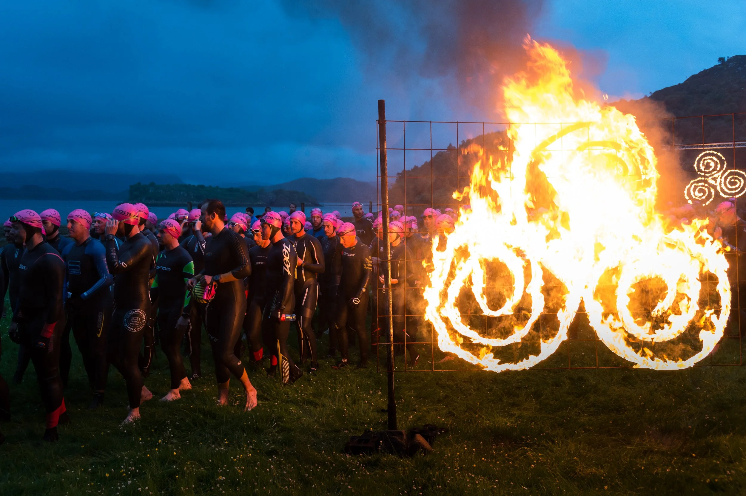 Competitors make their way towards the waters of Loch Shieldaig in front of a burning Celtman logo at the start of the Celtman Extreme Scottish Triathlon.
