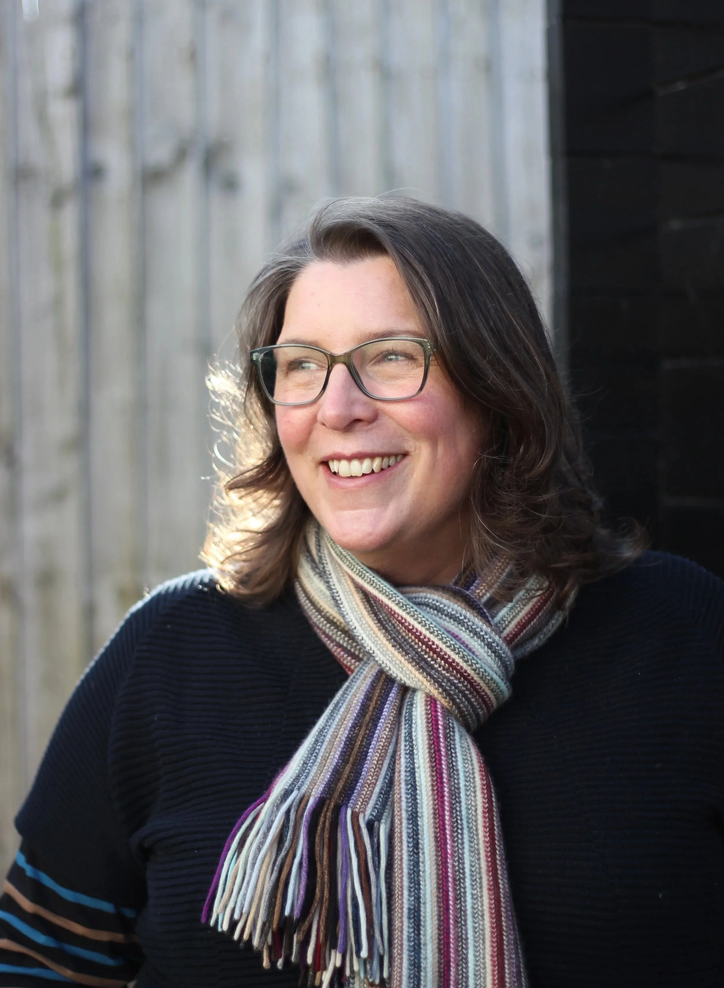 Su-Thompson-ceramics-standing-infront-of-garden-studio-sun-shining-through-her-hair